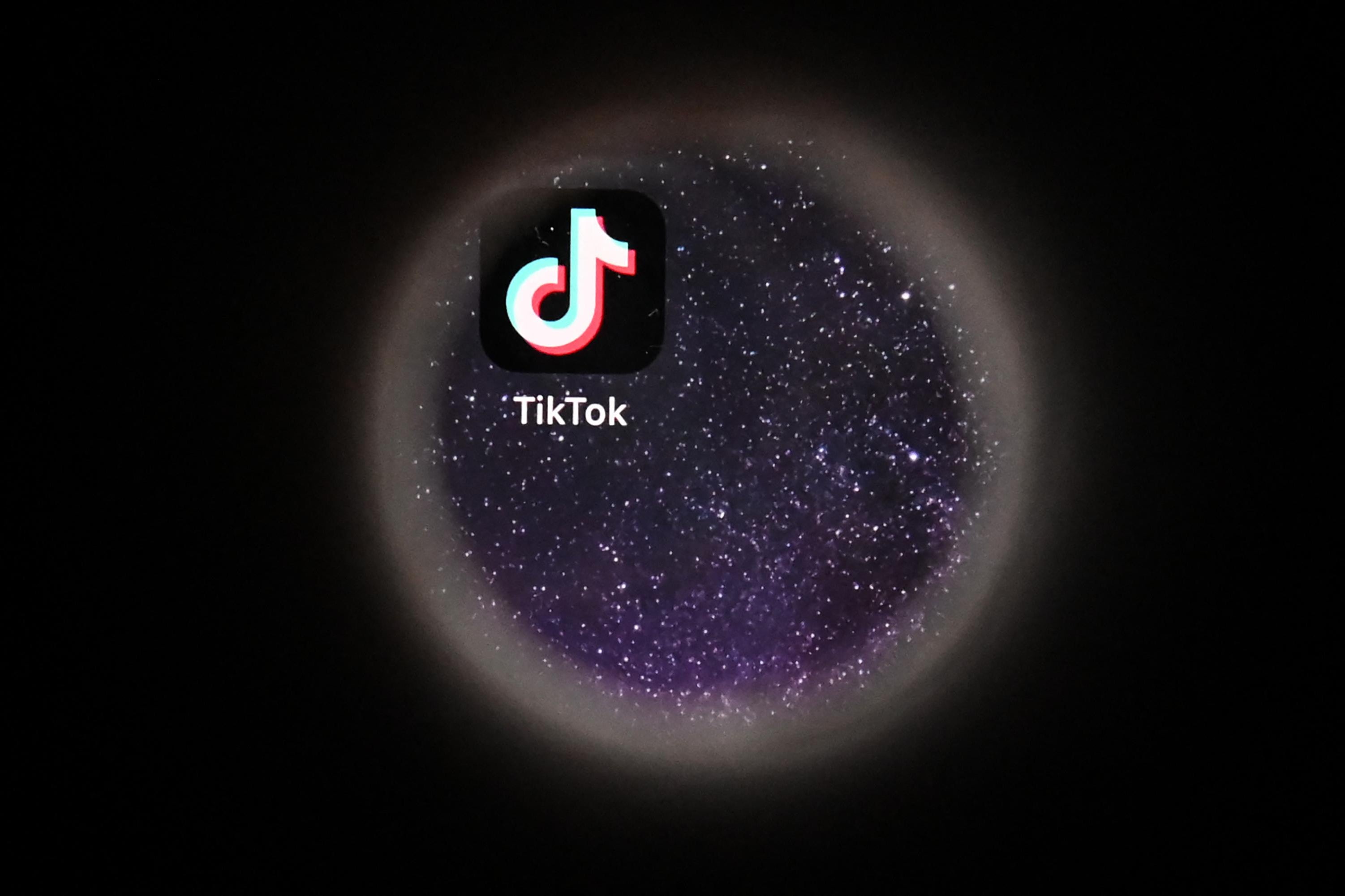 The TikTok logo, displayed against a starry background, is viewed through a circular lens.