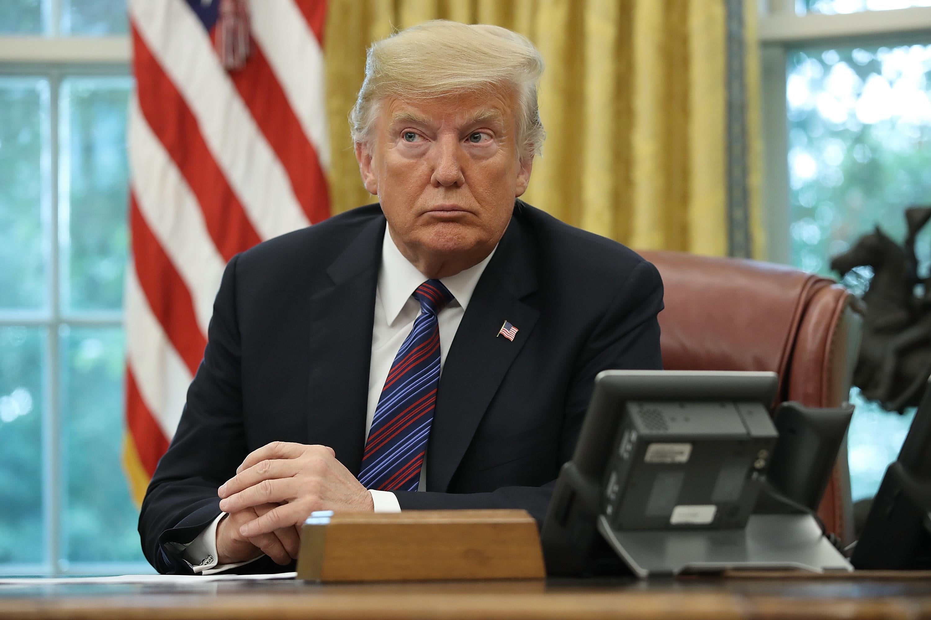 President Trump speaks on the telephone via speakerphone at the desk in the Oval Office.