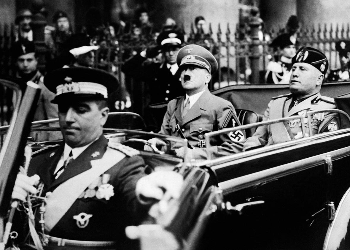 A picture taken in September 1937, in Munich, shows German Chancellor Adolf Hitler riding in a car with Italian dictator Benito Mussolini while the crowd gives the fascist salute. 