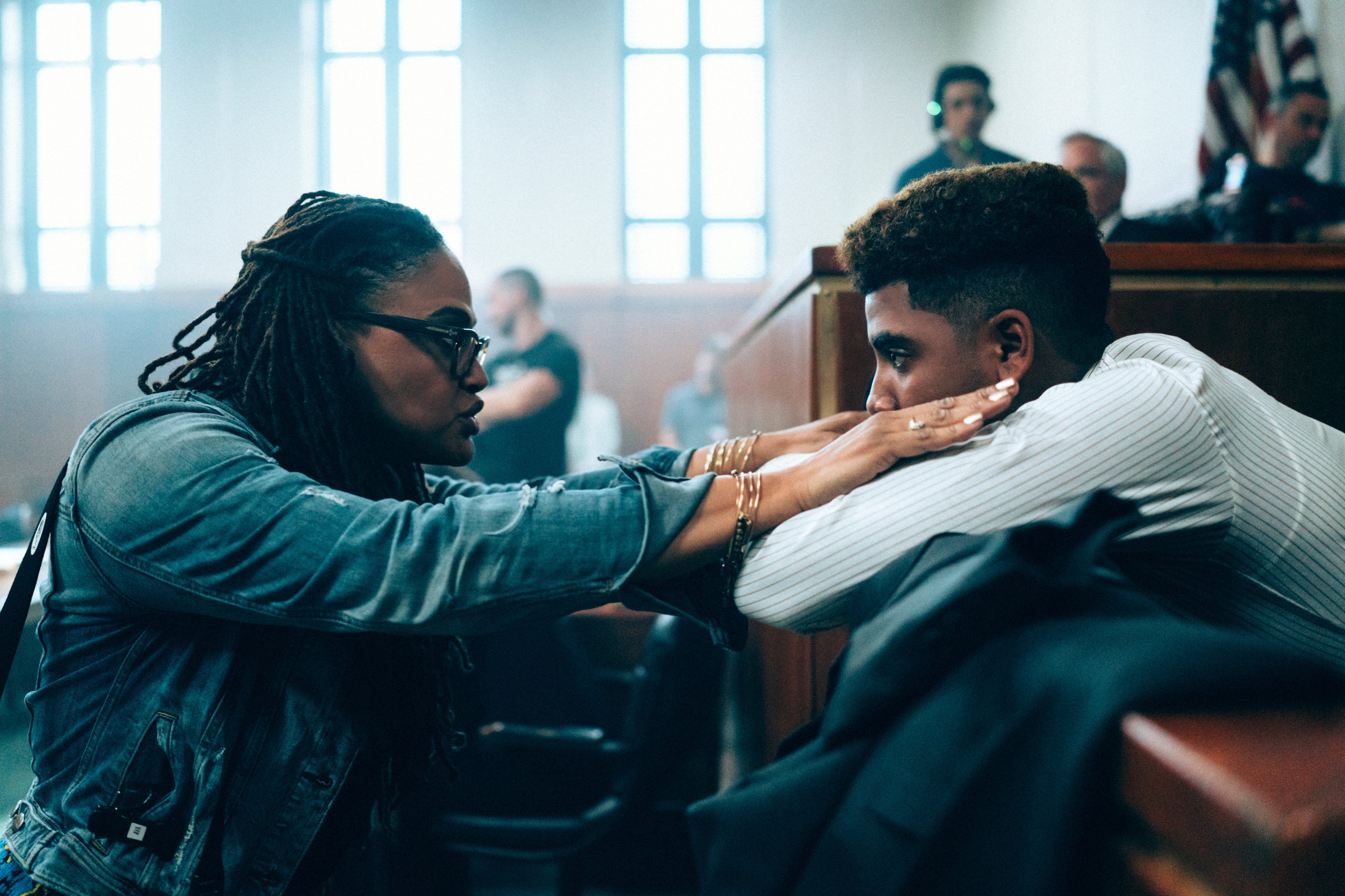 Ava DuVernay and Jharrel Jerome on the set of a courtroom.