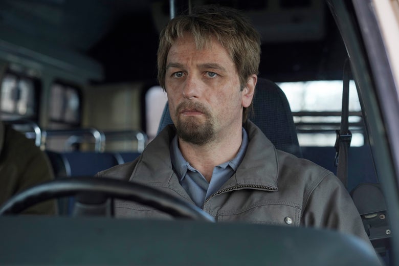 Matthew Rhys as Philip in The Americans. He sits in a car looking haggard, with limp, dirty-blonde hair and a goatee.