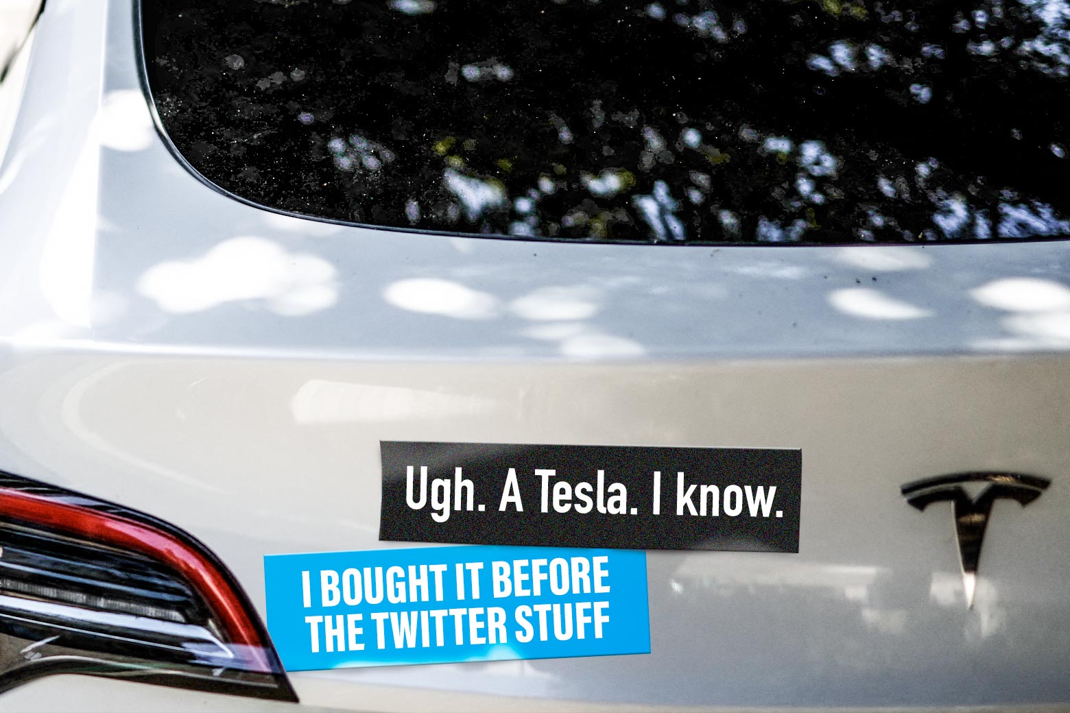 A Tesla with bumper stickers that are rude.