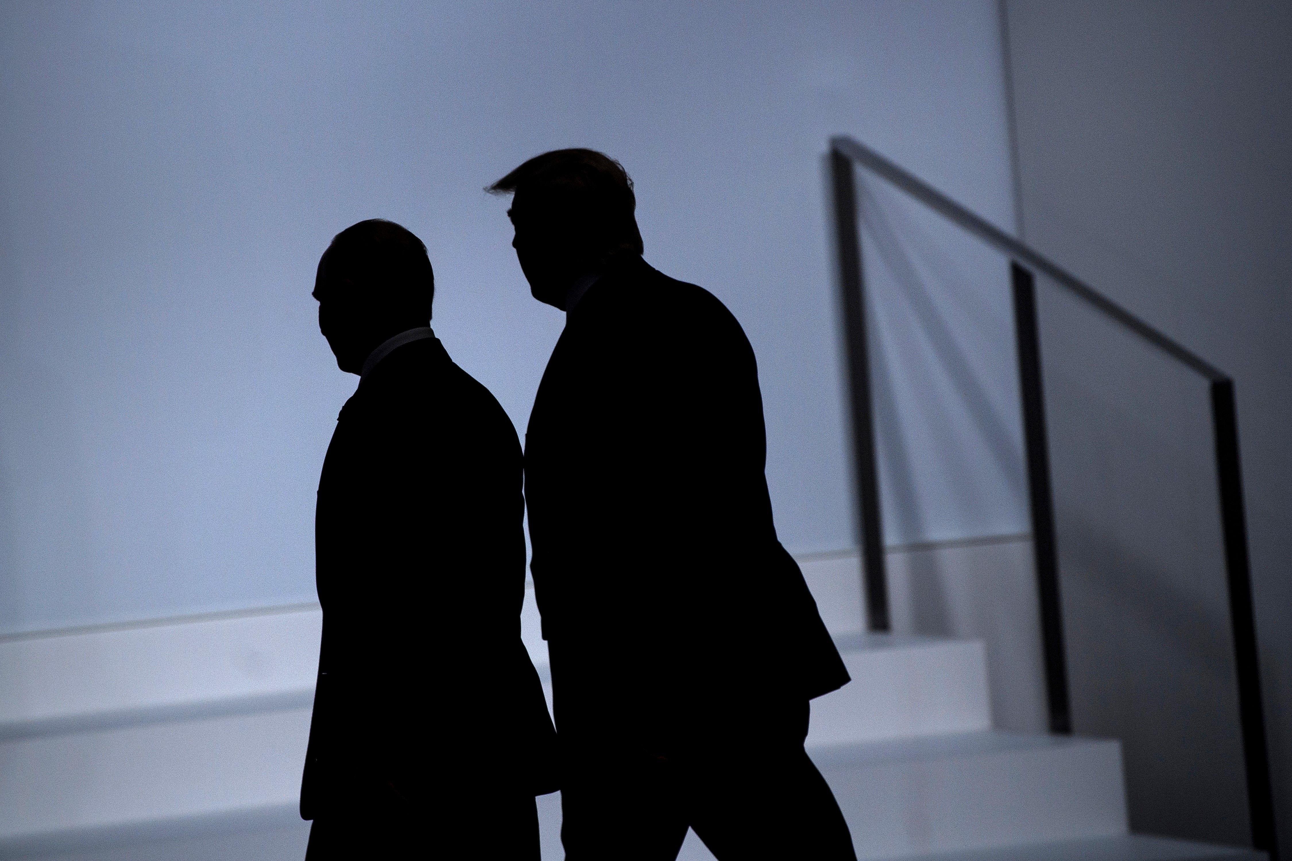 Trump and Putin walking together, seen in silhouette.