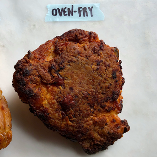 A thickly battered, dark brown chicken thigh labeled Oven + Fry.