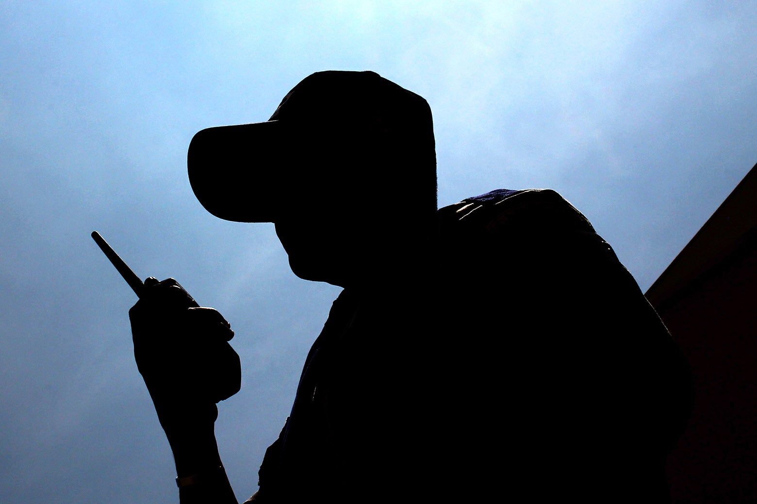 A silhouette of a man in a cap holding a walkie-talkie