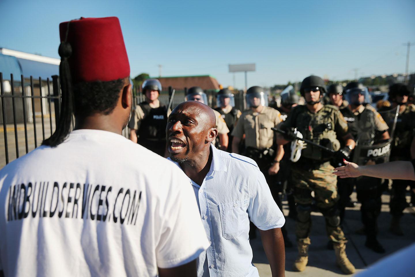 A demonstrator, protesting the shooting death of teenager Michael Brown, pleads with another to walk away after being ordered off the street by police on August 13, 2014 in Ferguson, Missouri. 