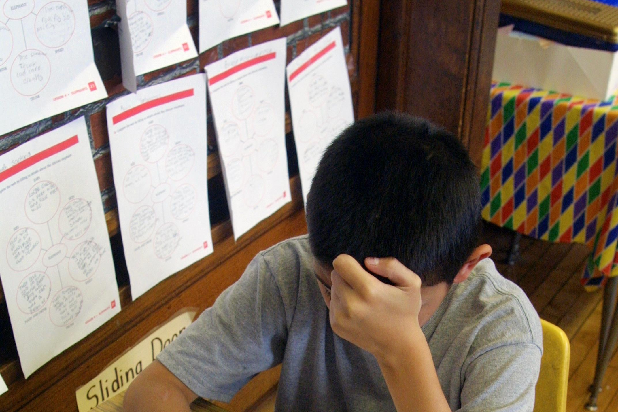 A middle school student holding a pencil works to solve a problem at a desk.