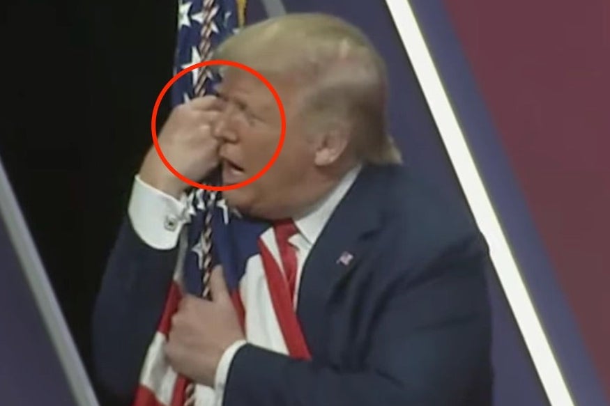 Trump hugging a flag, his face is pressed against his hadn