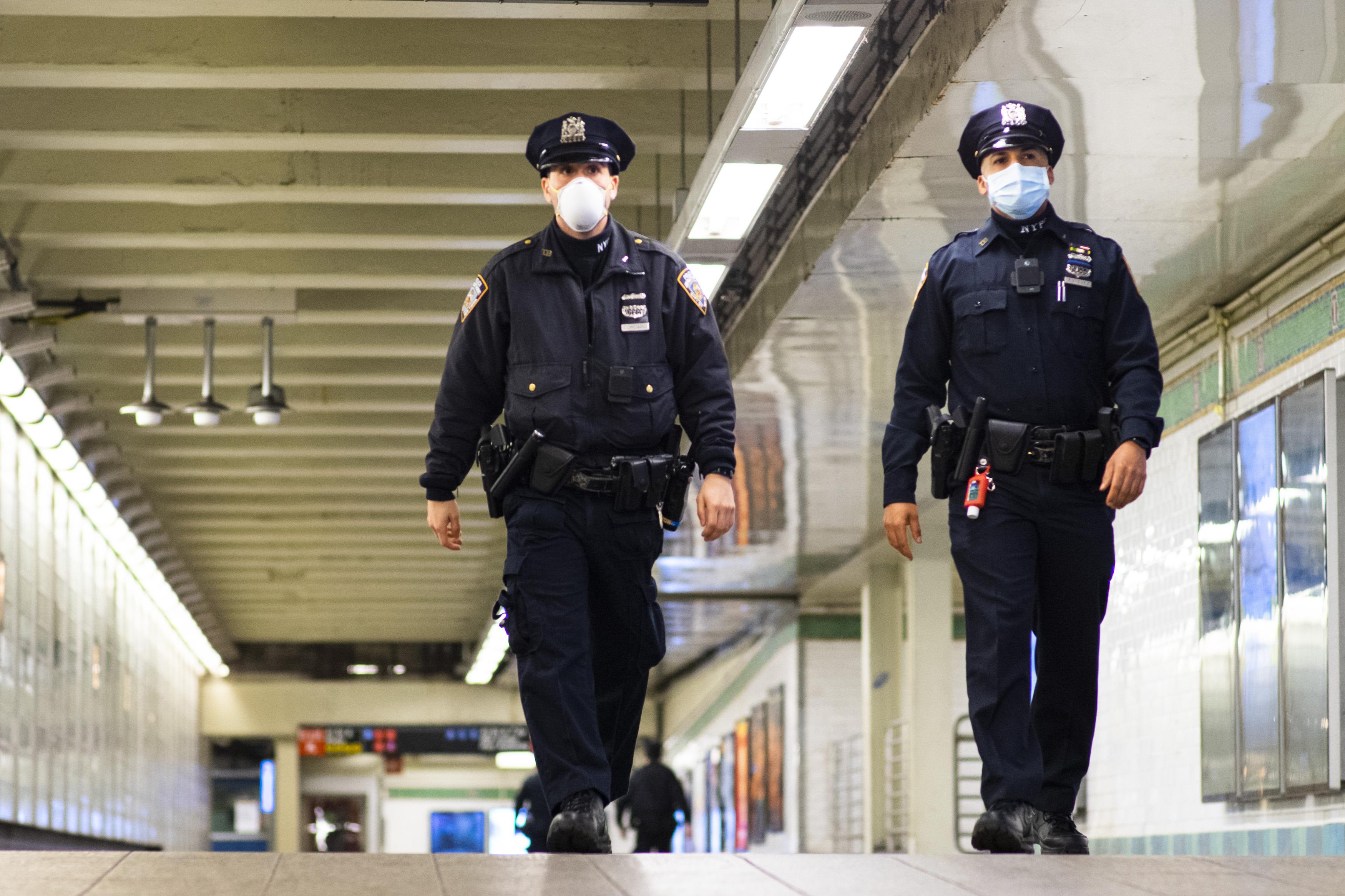NYPD officers wearing face masks patrol inside a subway station.