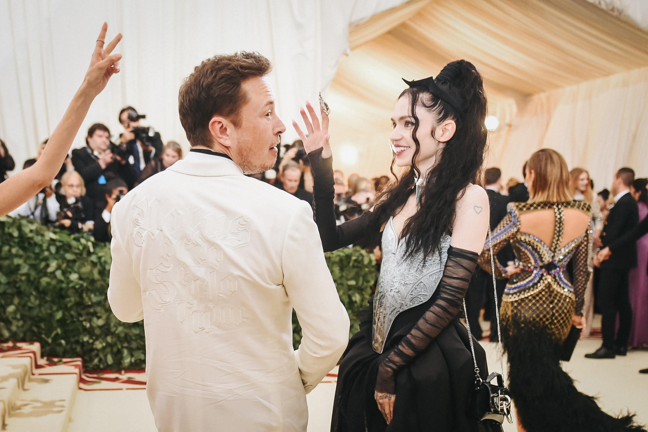 Elon Musk and Grimes, he from behind, she in profile, on the red carpet for the Met Gala in 2018.