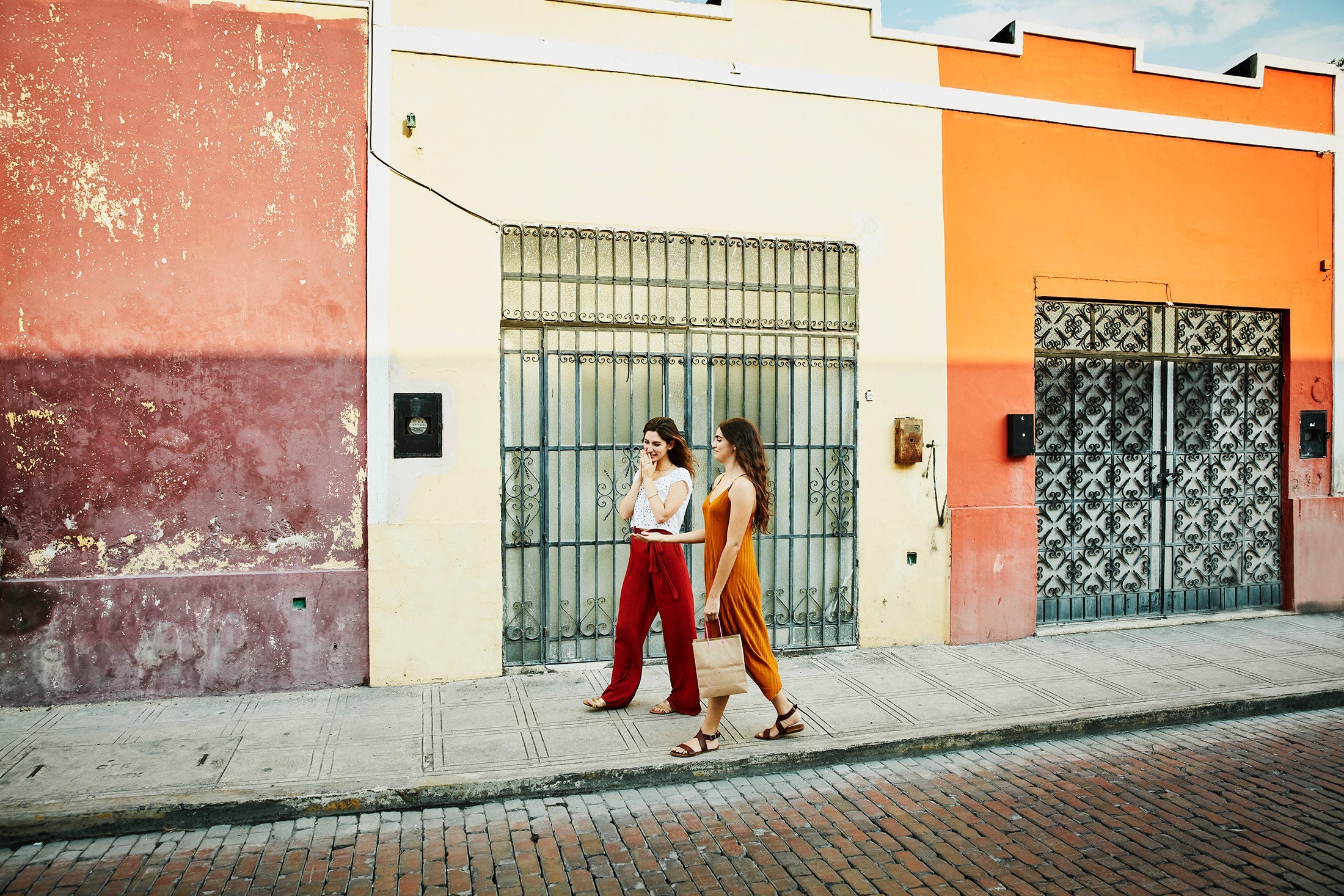 Two women walking down a brightly painted street.