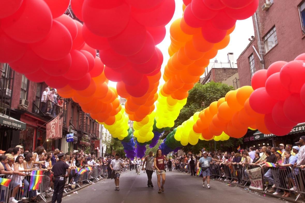 Rainbow balloons over a street during a Pride parade.