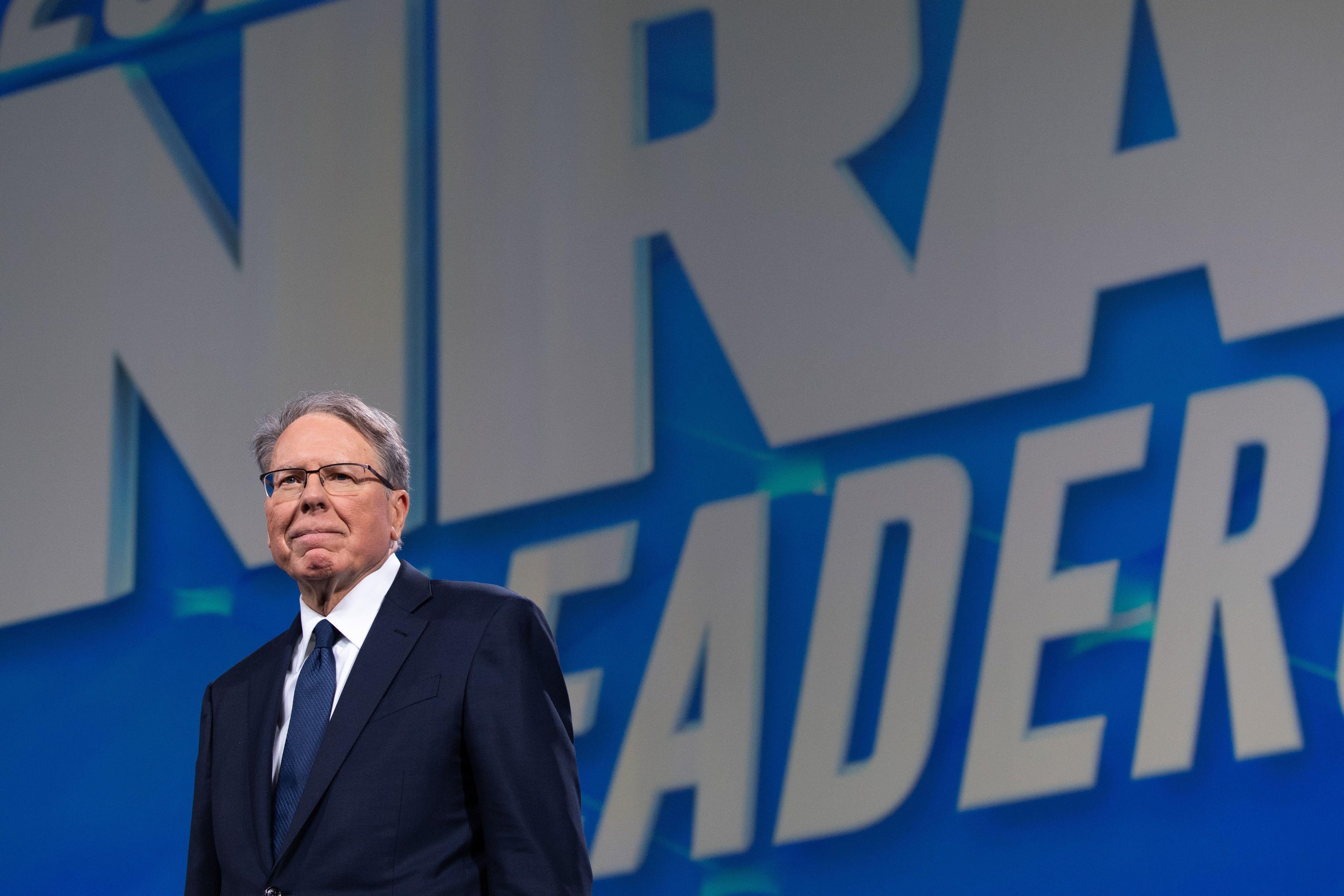 LaPierre standing in front of an NRA banner
