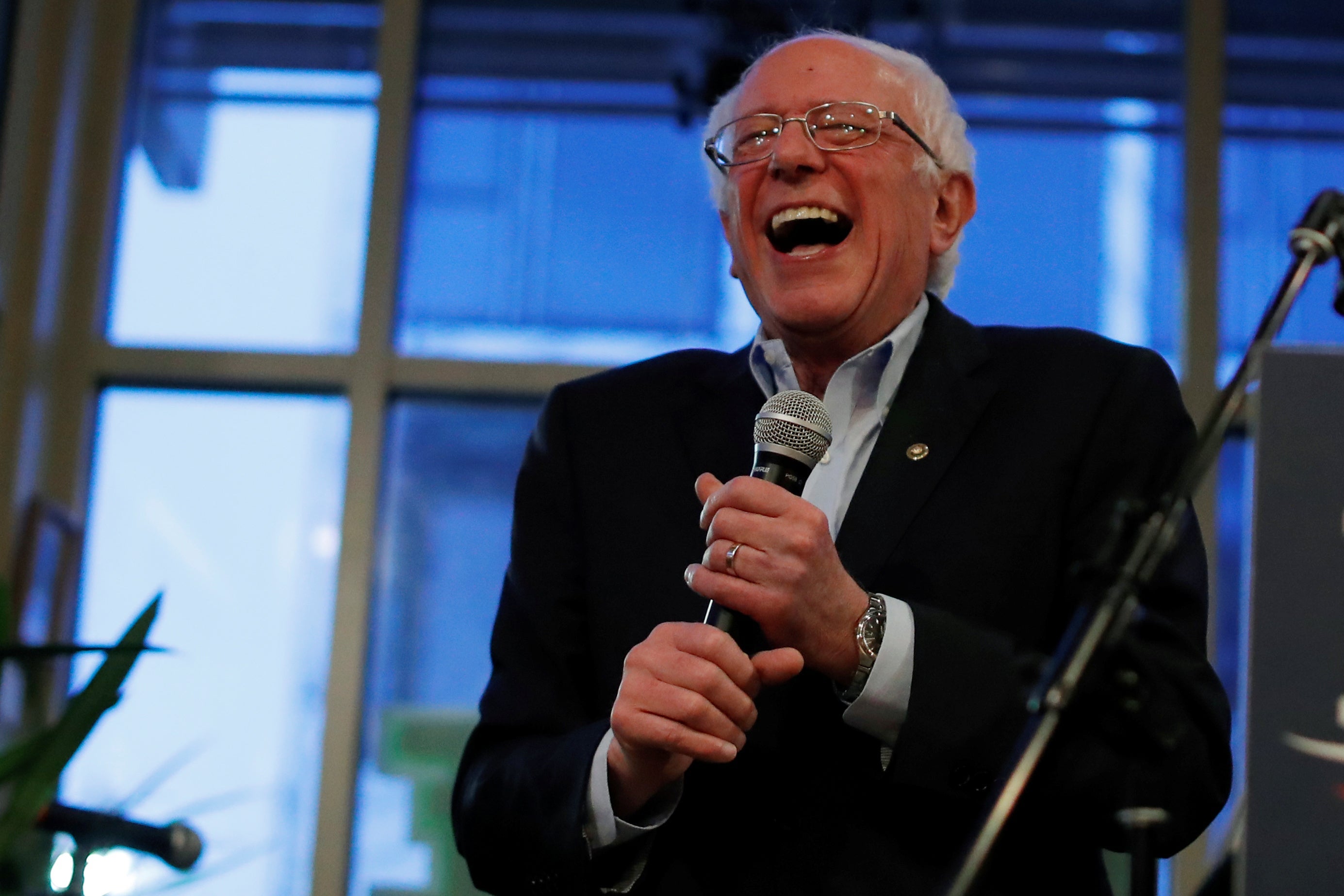 Bernie Sanders laughing while holding a mic