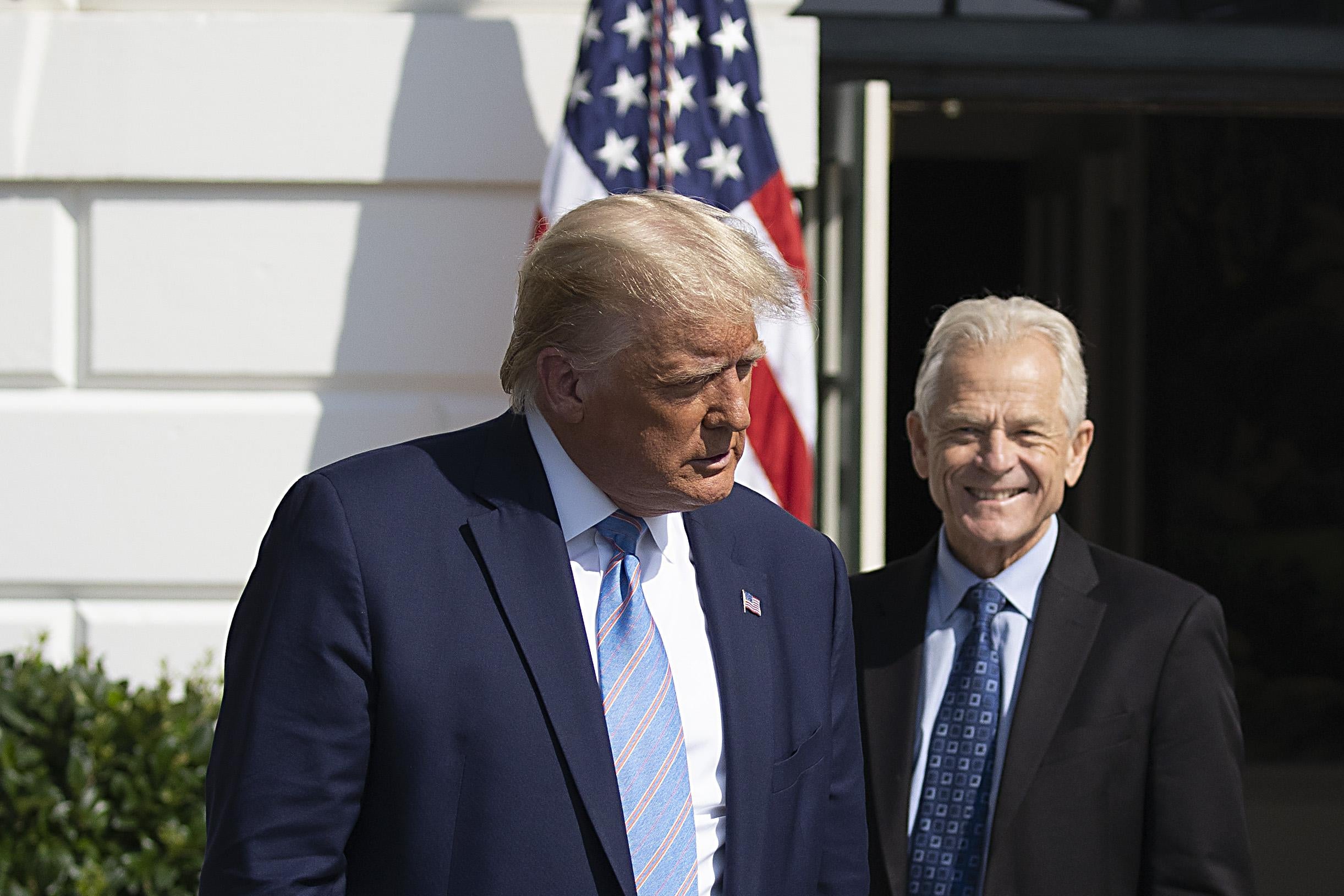 Navarro smiles, standing near Trump outside