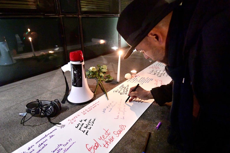 A man writes on a white sheet. There are candles.