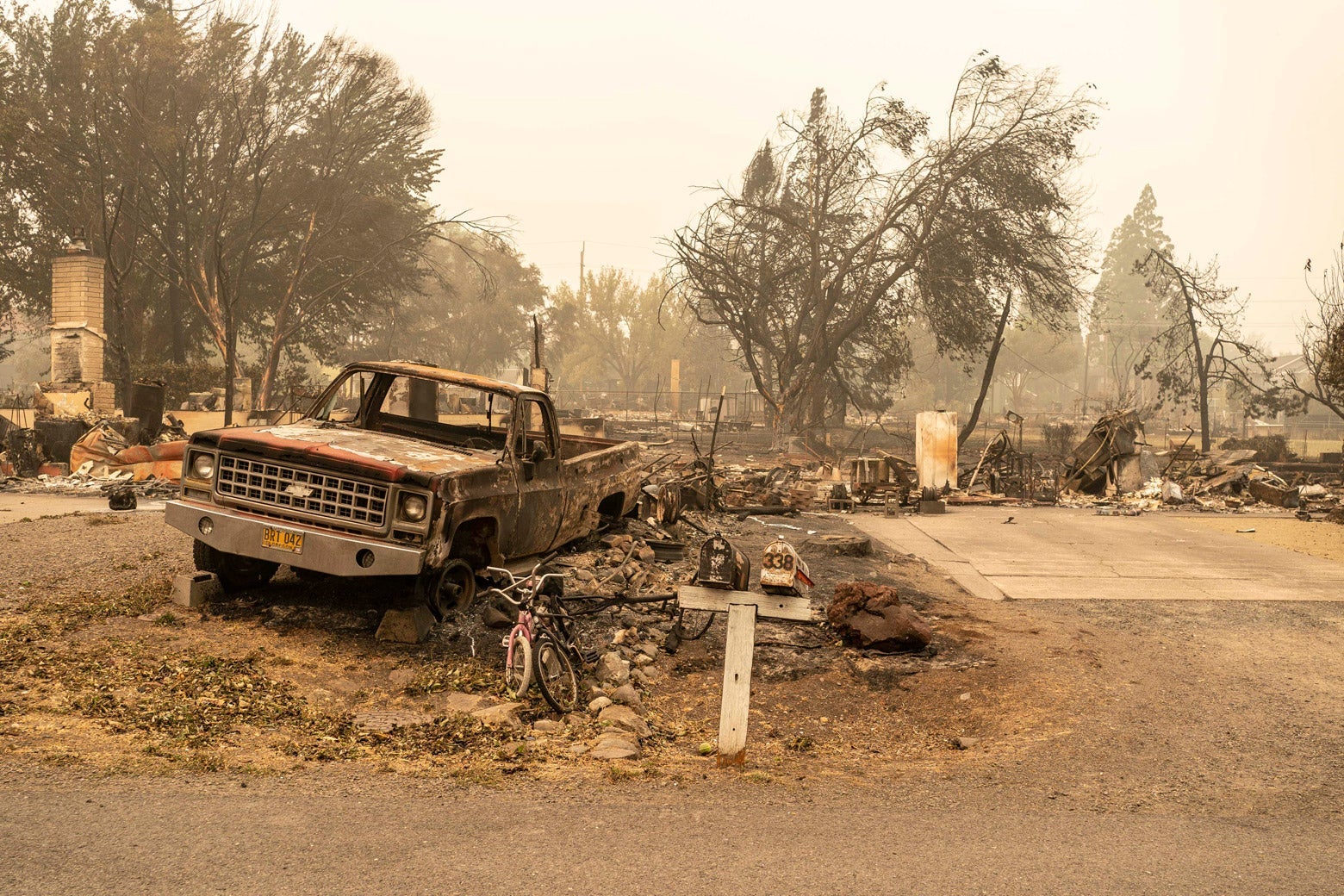 A burnt pickup truck sits in front of a scorched area.