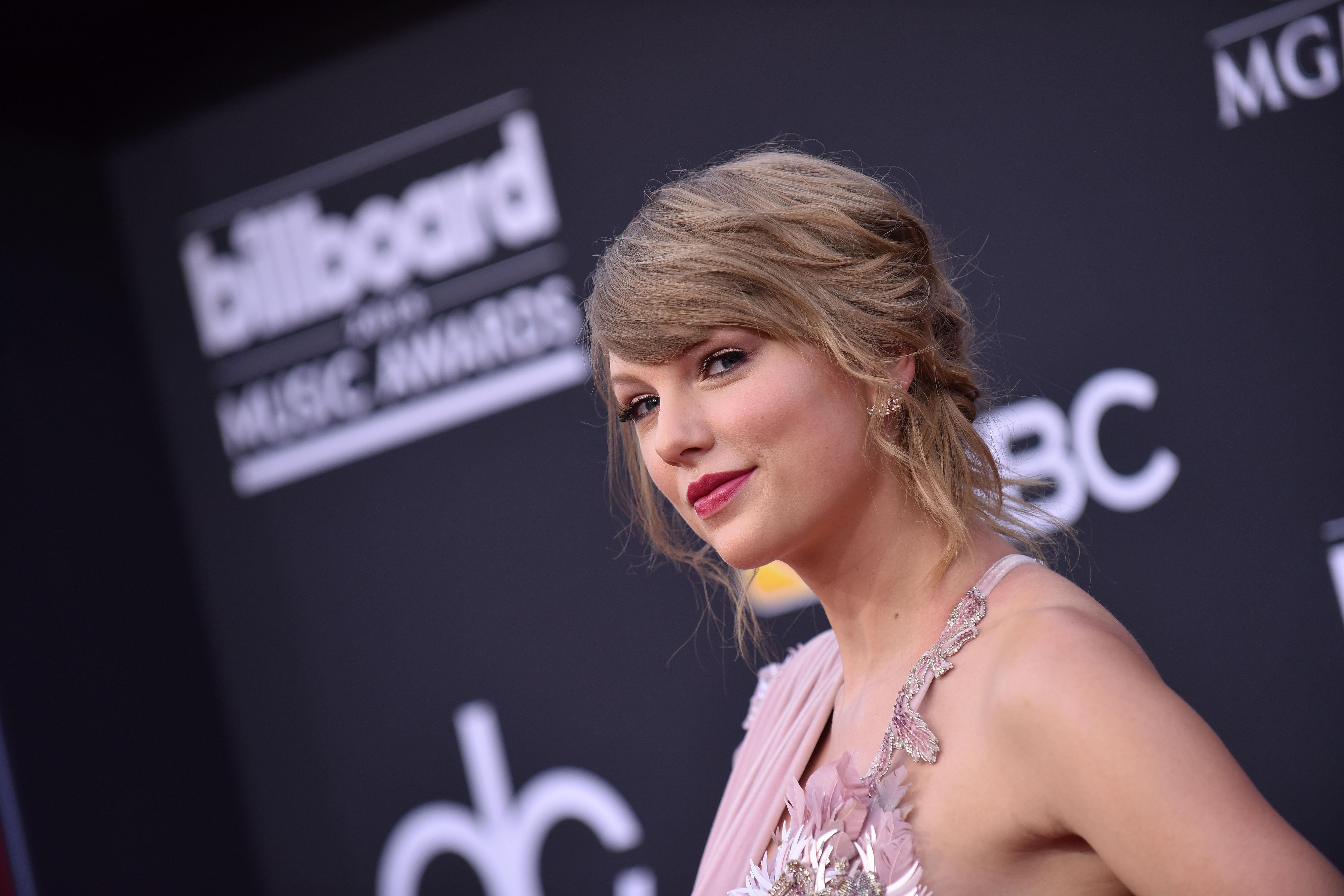 Taylor Swift on the red carpet smirks into the camera.
