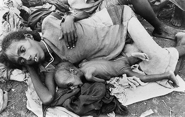 A starving mother and a child wait for food at a relief camp in the province of Wollo, Ethiopia, during a widespread famine in December 1984.