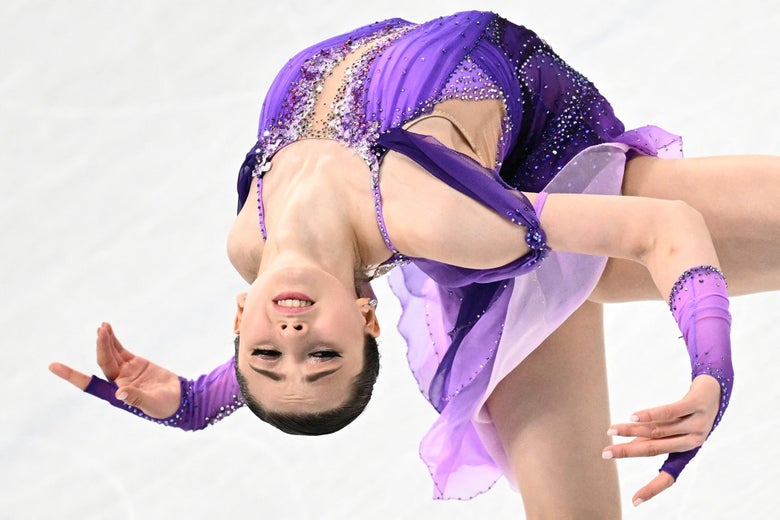 Valieva bending backward with her arms out as she skates on the ice