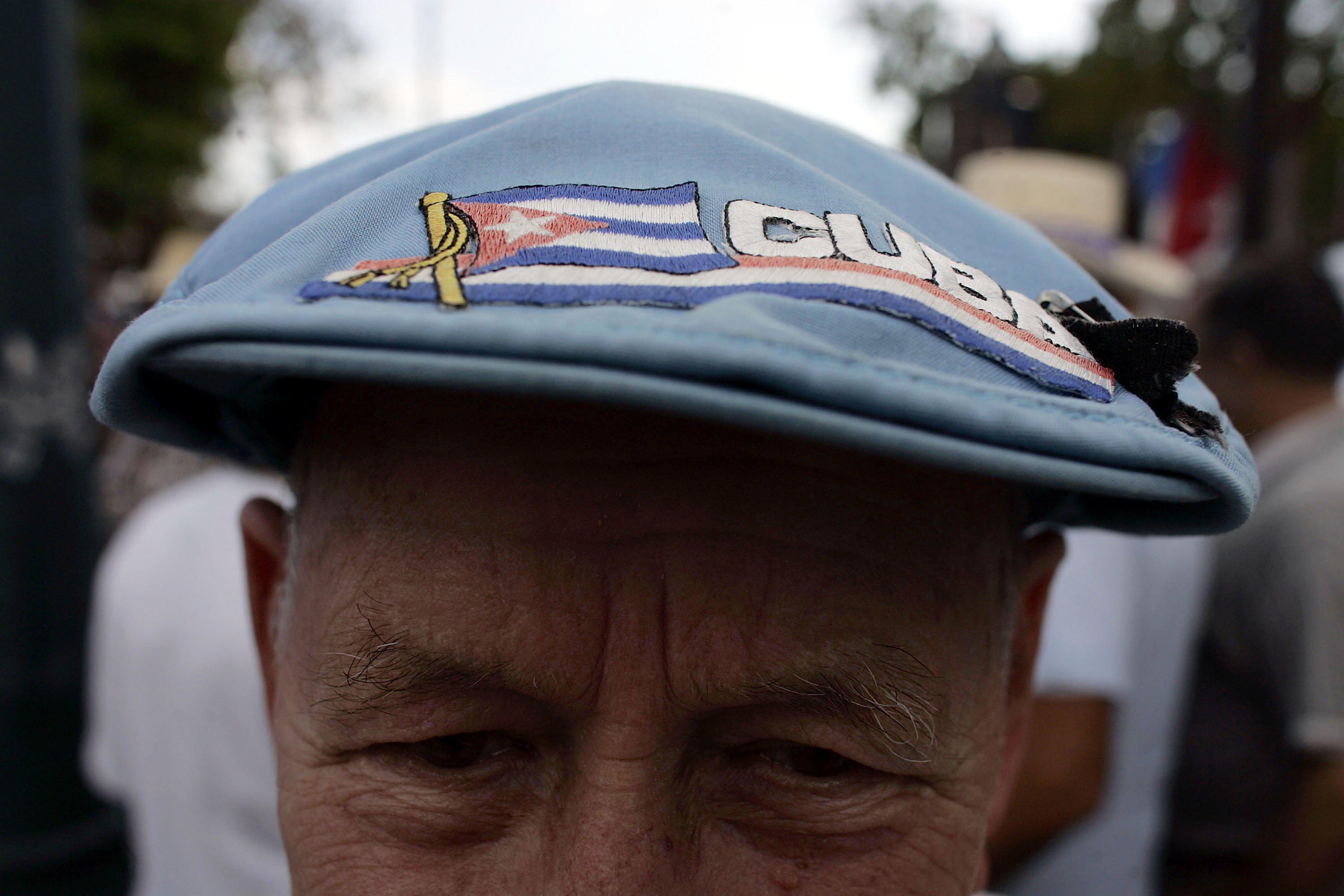 A close-up of a man's cap that says Cuba and features a Cuban flag.