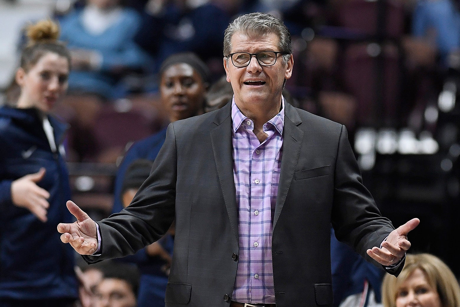 Geno Auriemma standing with his arms outstretched at a basketball game.