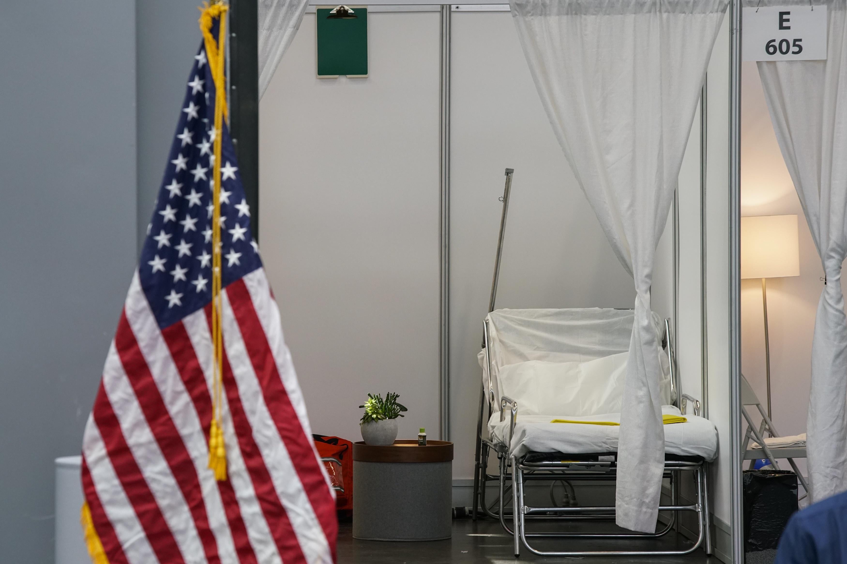 An improvised hospital room at the Javits Center with an American flag in front of it