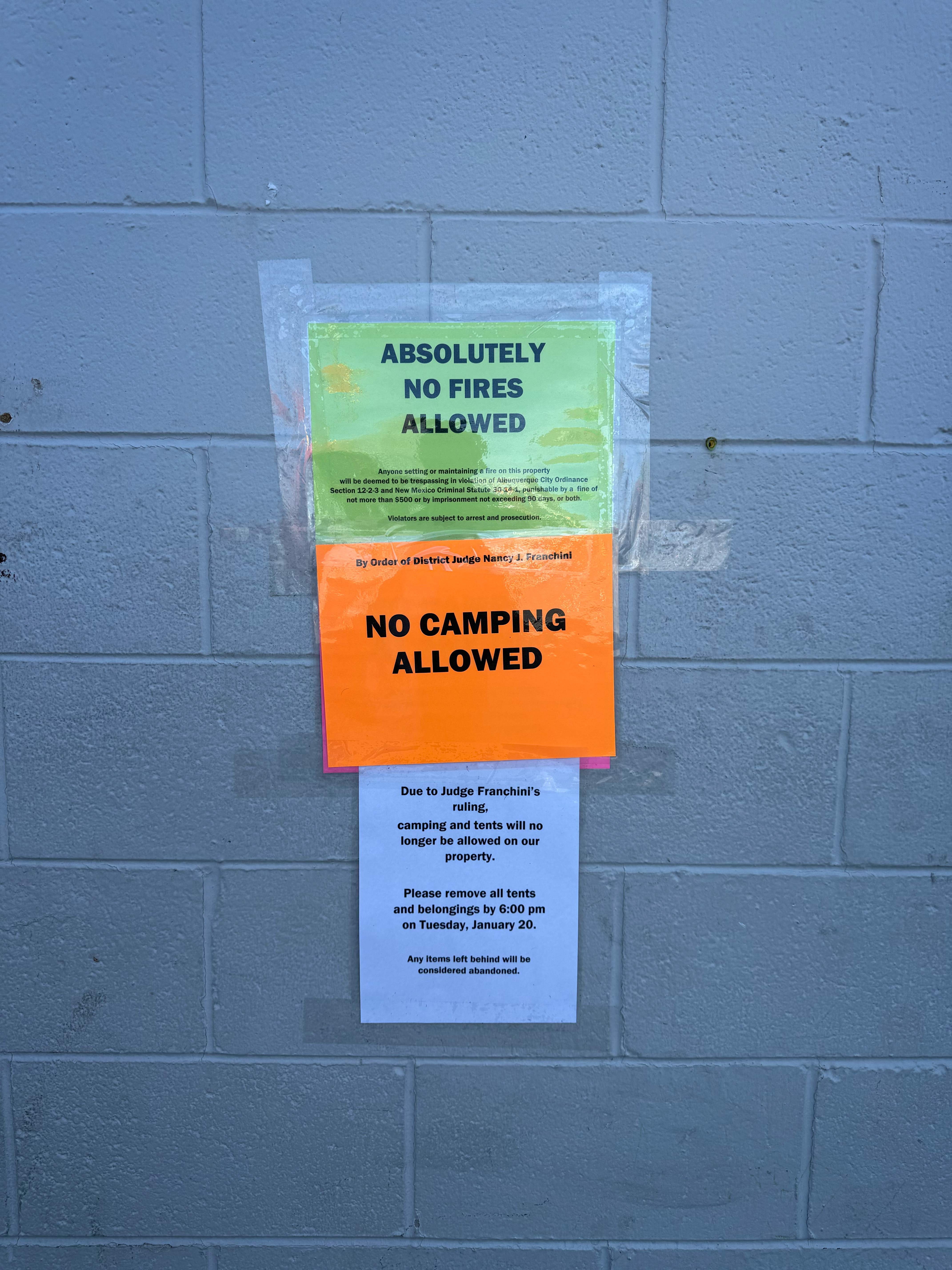 Laminated No Camping and No Fires notices on a brick wall.