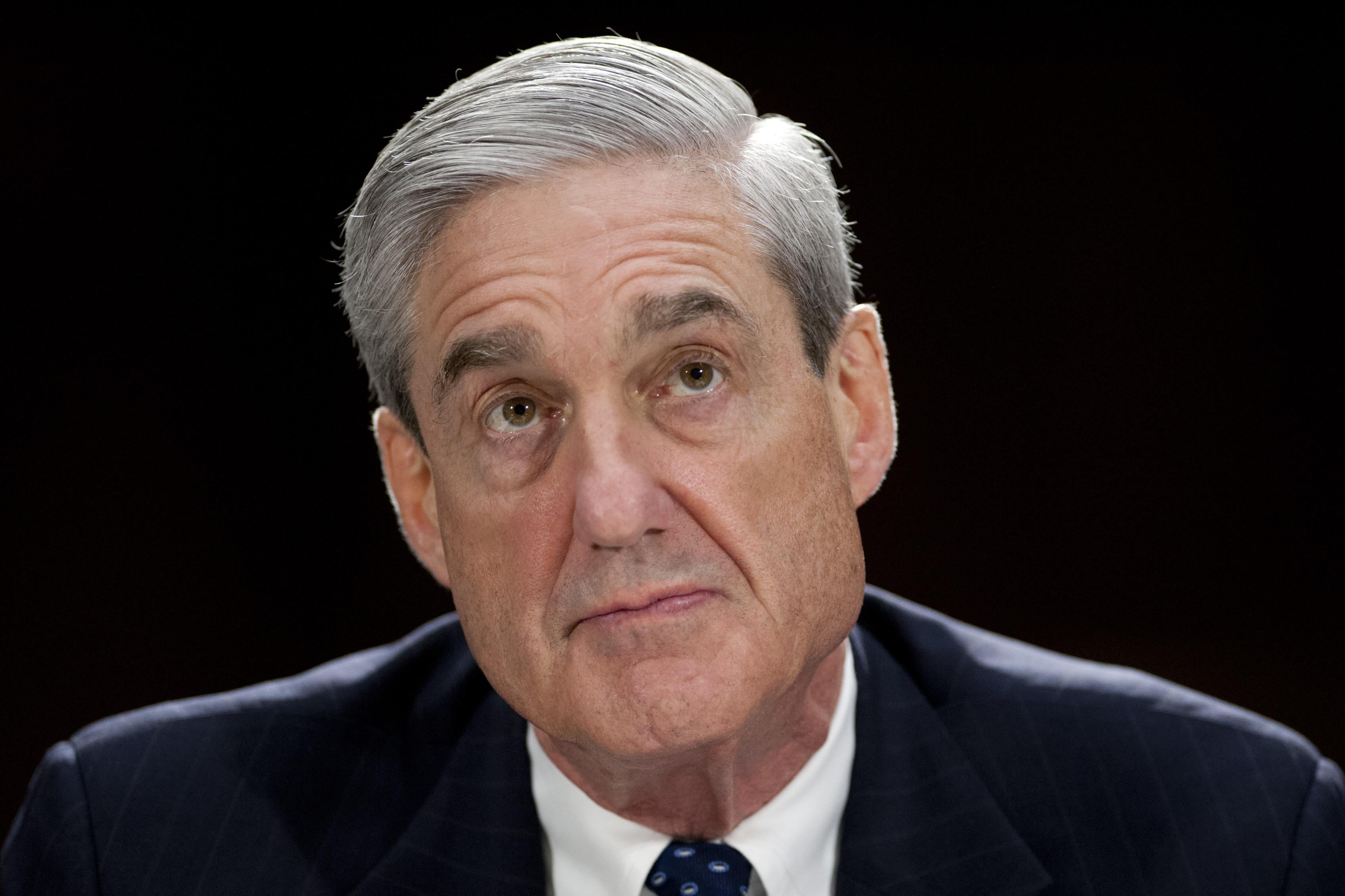 Mueller, in front of a background of black, looks upward.
