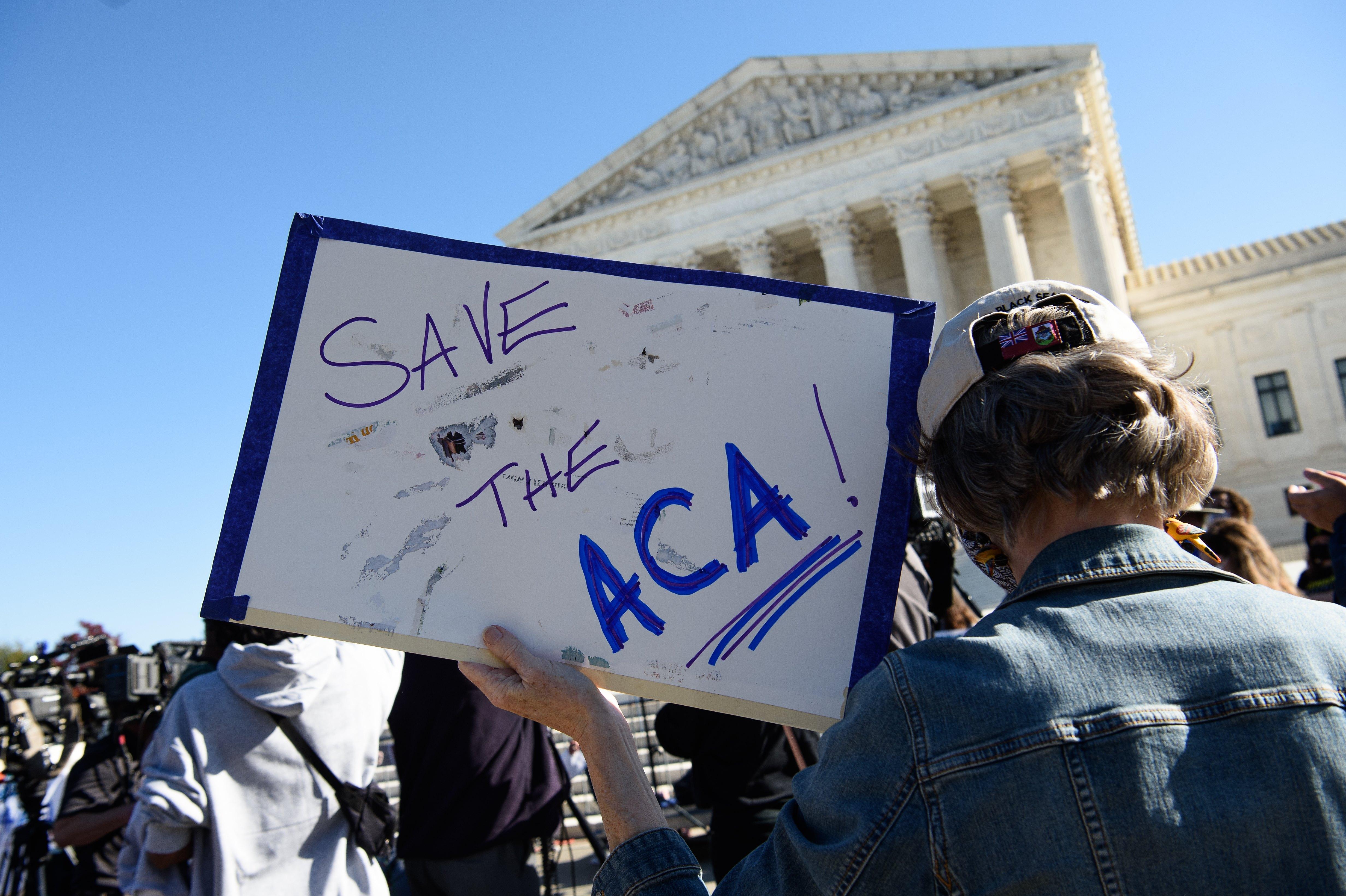 A demonstrator holds a sign in front of the US Supreme Court that says "Save the ACA."