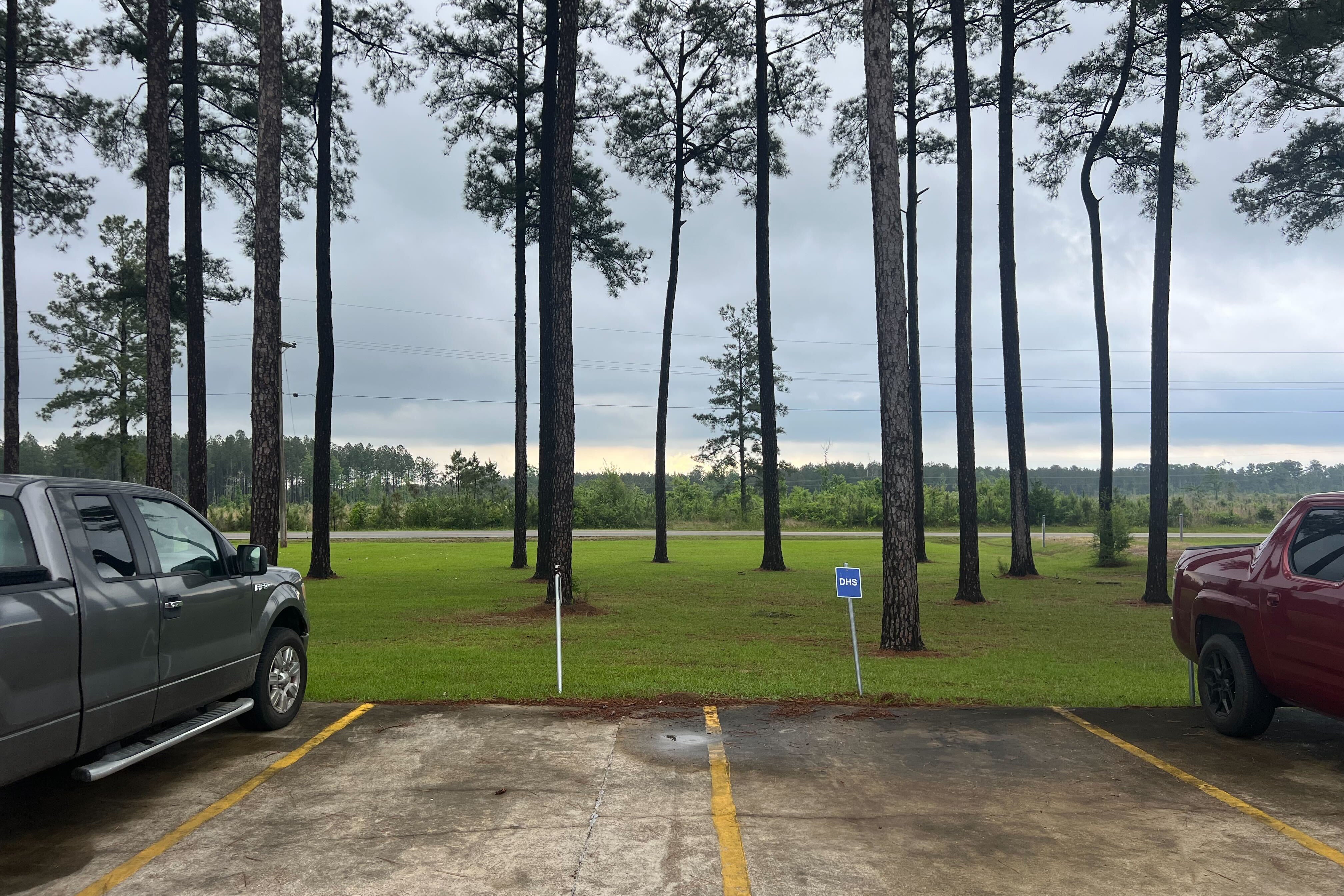 Two empty parking spaces at the detention facility, next to a dense forest.