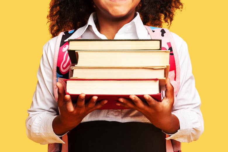 A woman holds a stack of books.