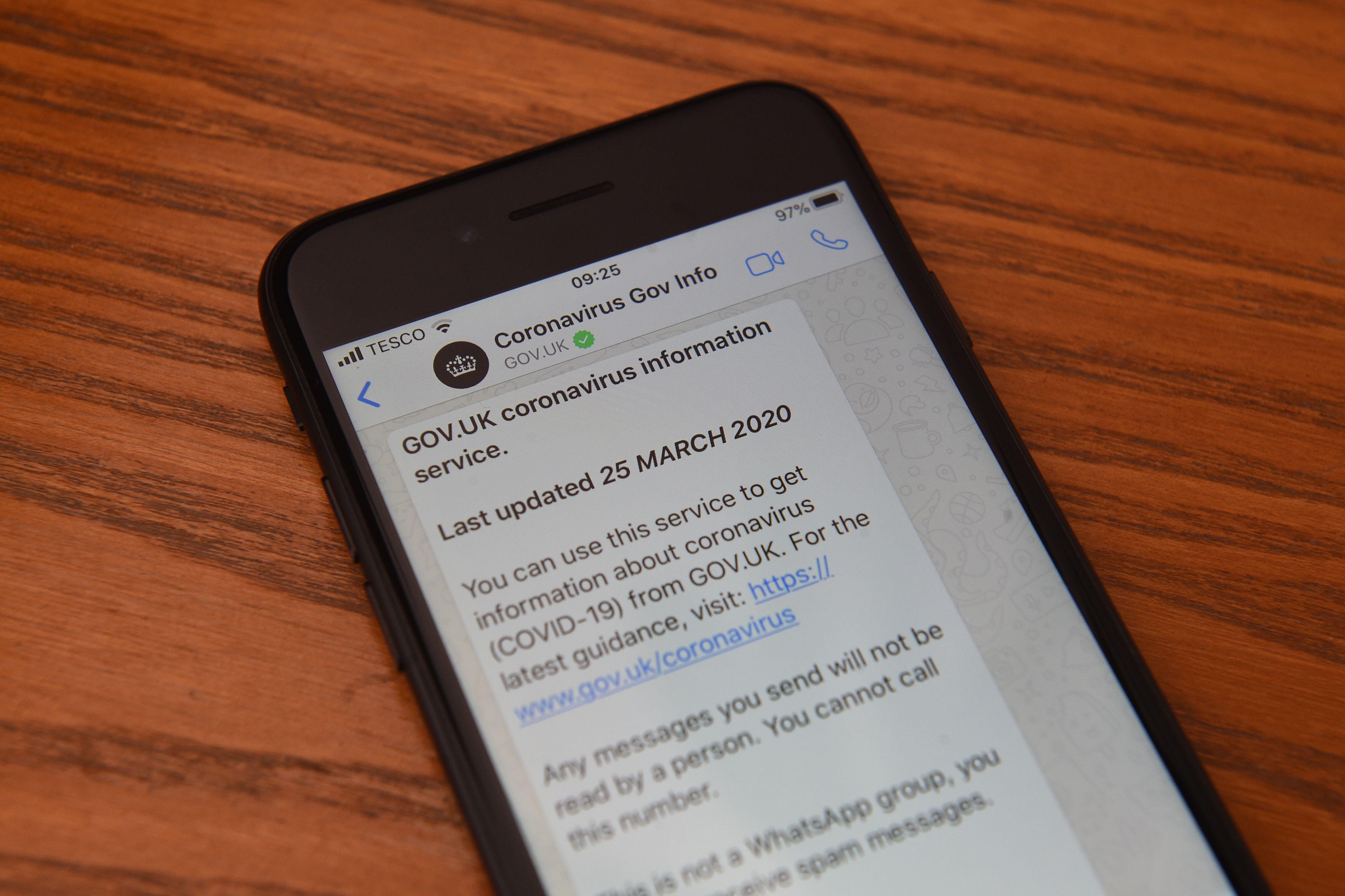 A smartphone displaying a WhatsApp message from "GOV.UK Coronavirus Information Service."