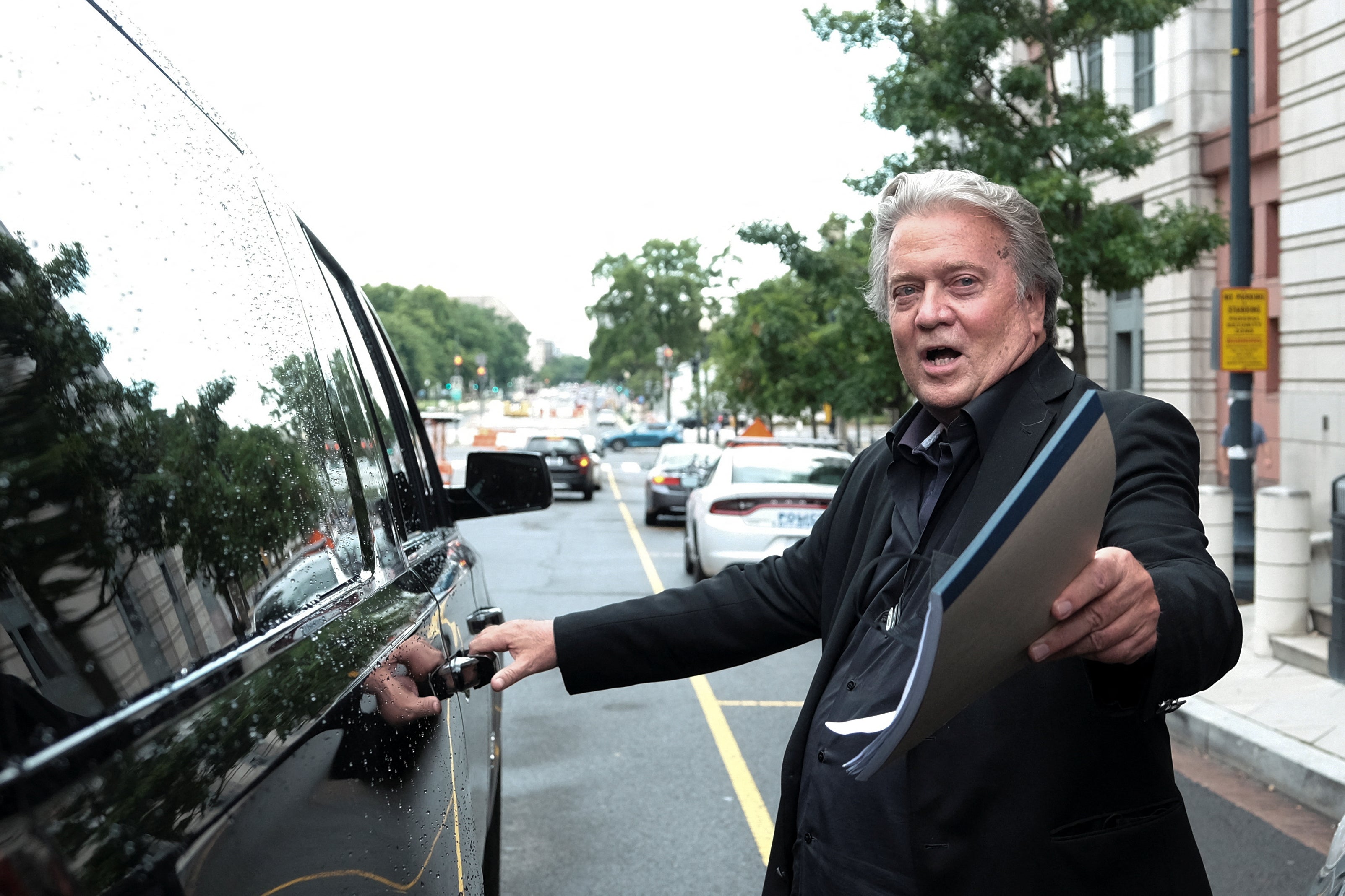Former Trump White House strategist Steve Bannon opens the door of a car and departs, following the first day of his trial in Washington, D.C.