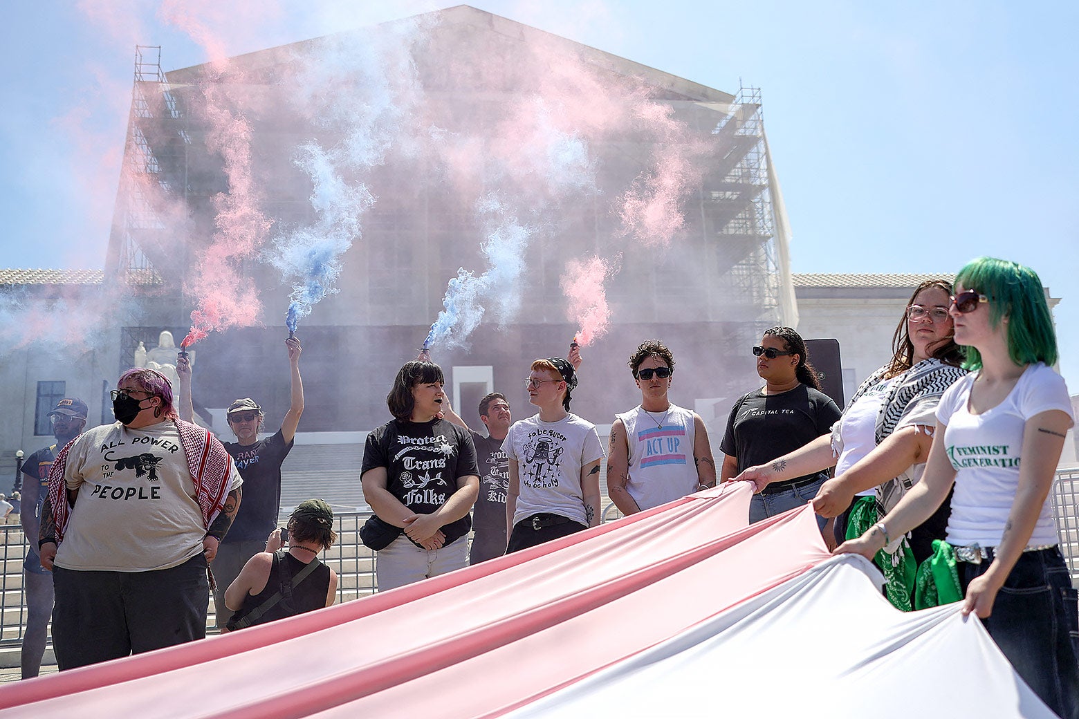 Demonstrators hold colored smoke devices and flags during a rally.