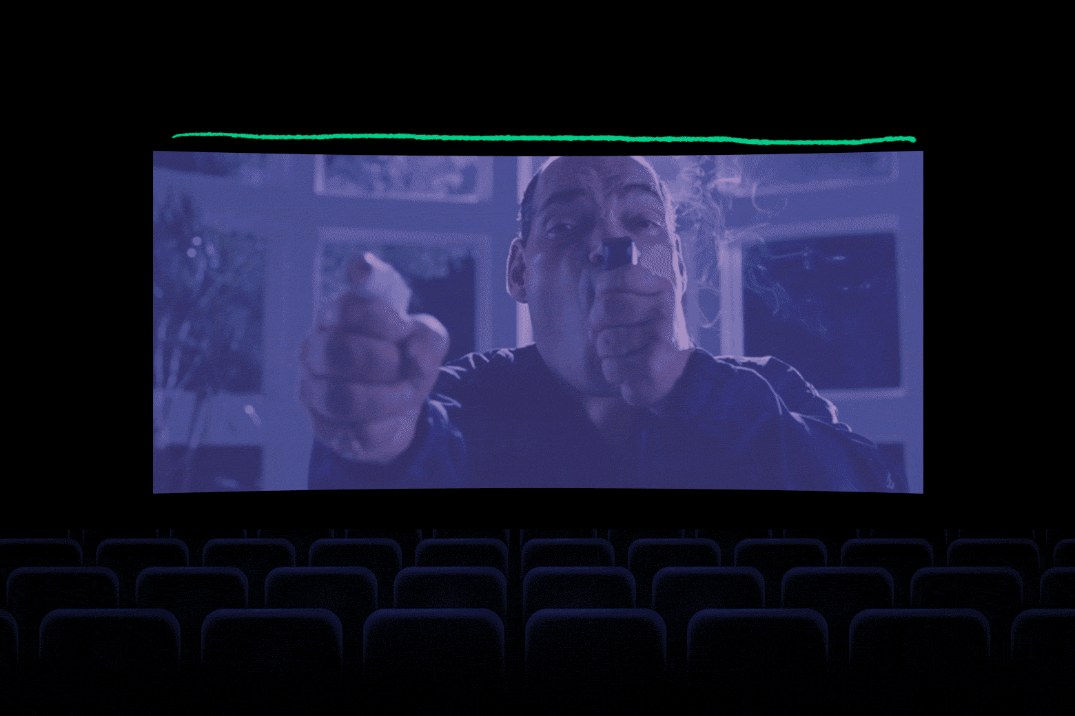An empty movie theater's screen shows Wheezy Joe shooting himself in the mouth and George Clooney's character reacting