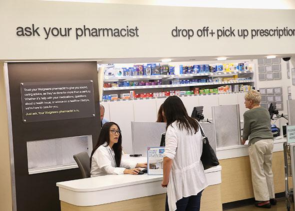 Pharmacist Jeanie Kim, left, consults with a customer at a Walgreens pharmacy on September 19, 2013 in Wheeling, Illinois.