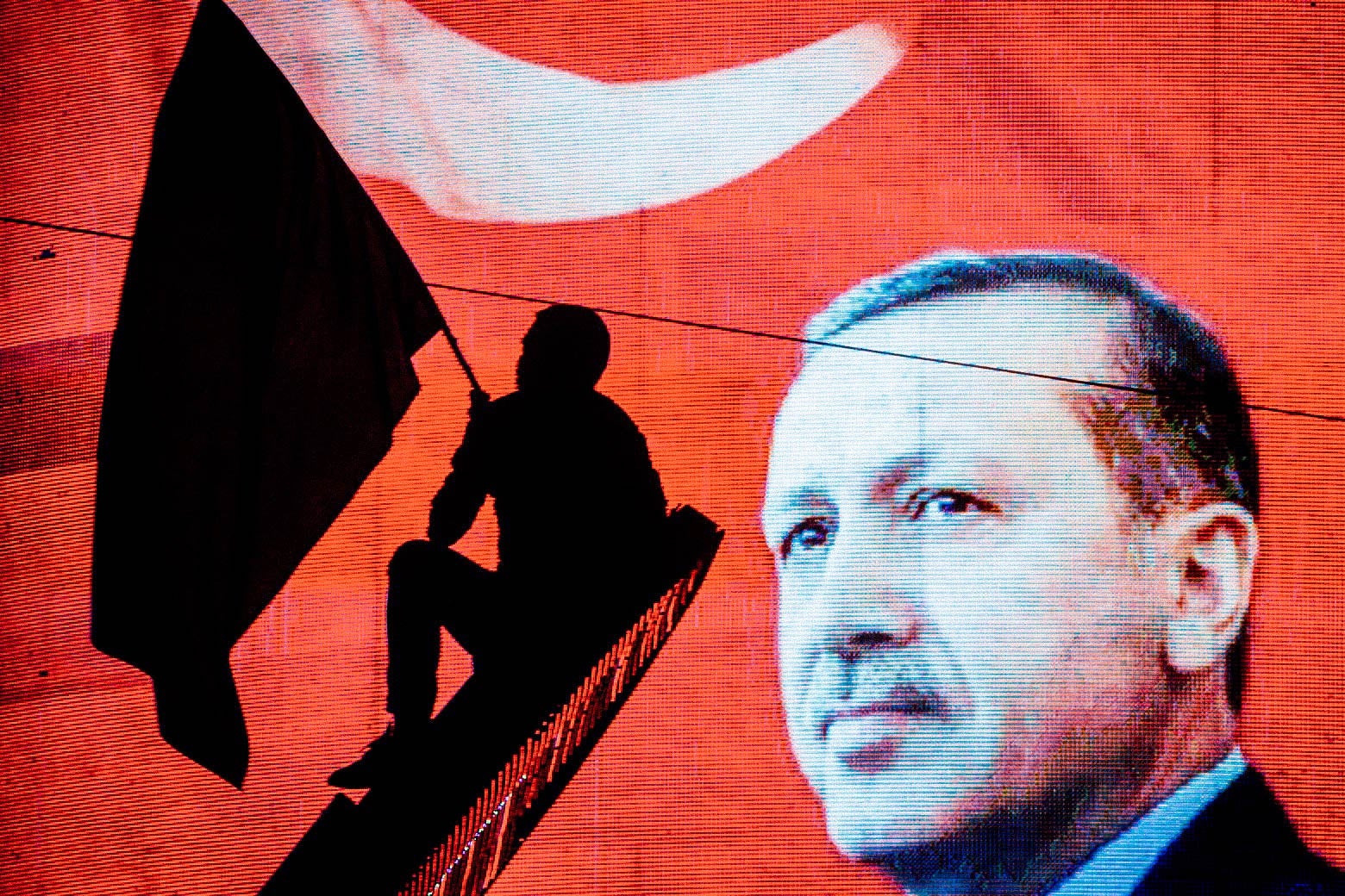 A man in silhouette waves a flag against the background of an electronic billboard depicting Erdogan and the Turkish flag.