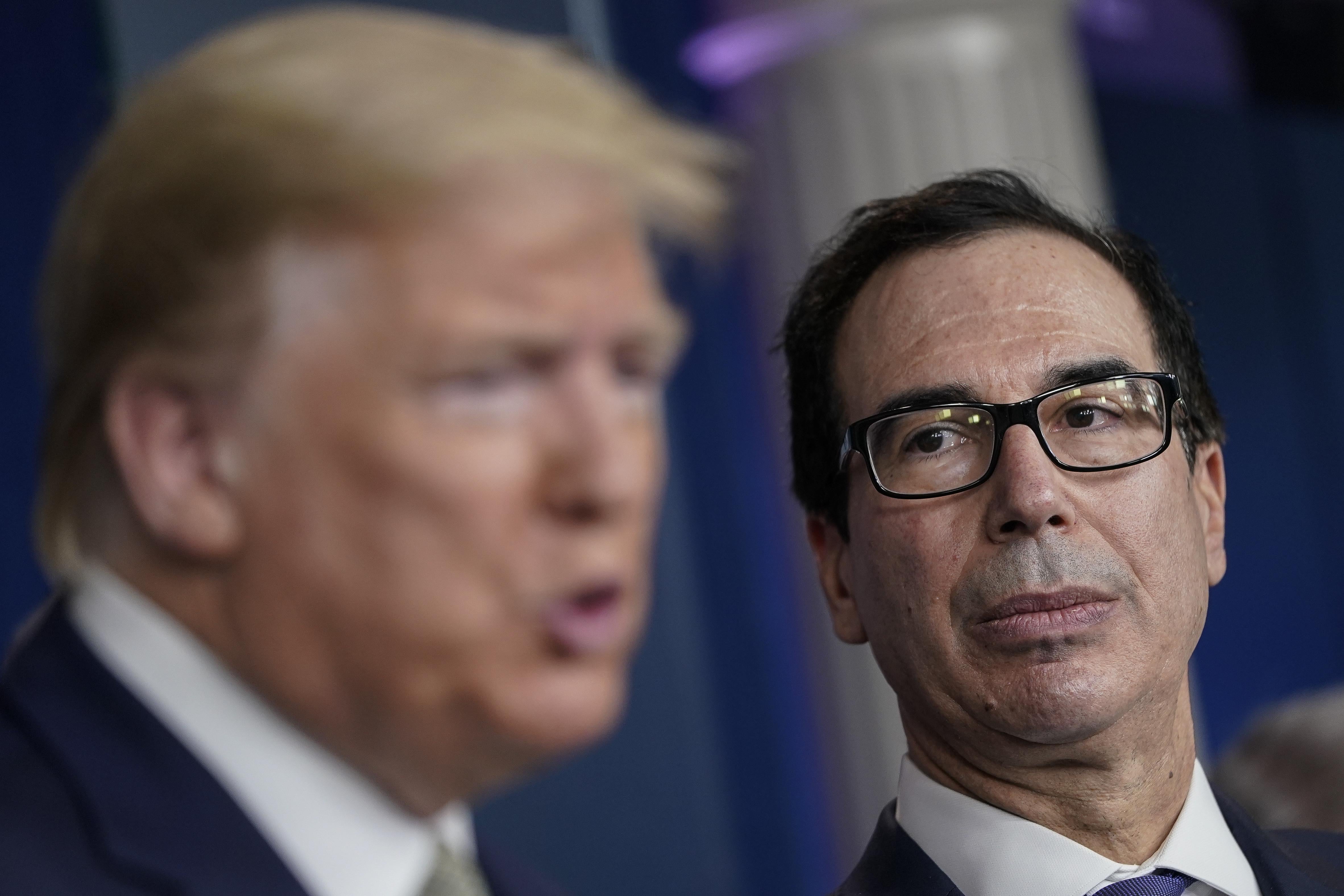 Steven Mnuchin, in focus, looks on as President Donald Trump speaks at the White House on Tuesday.
