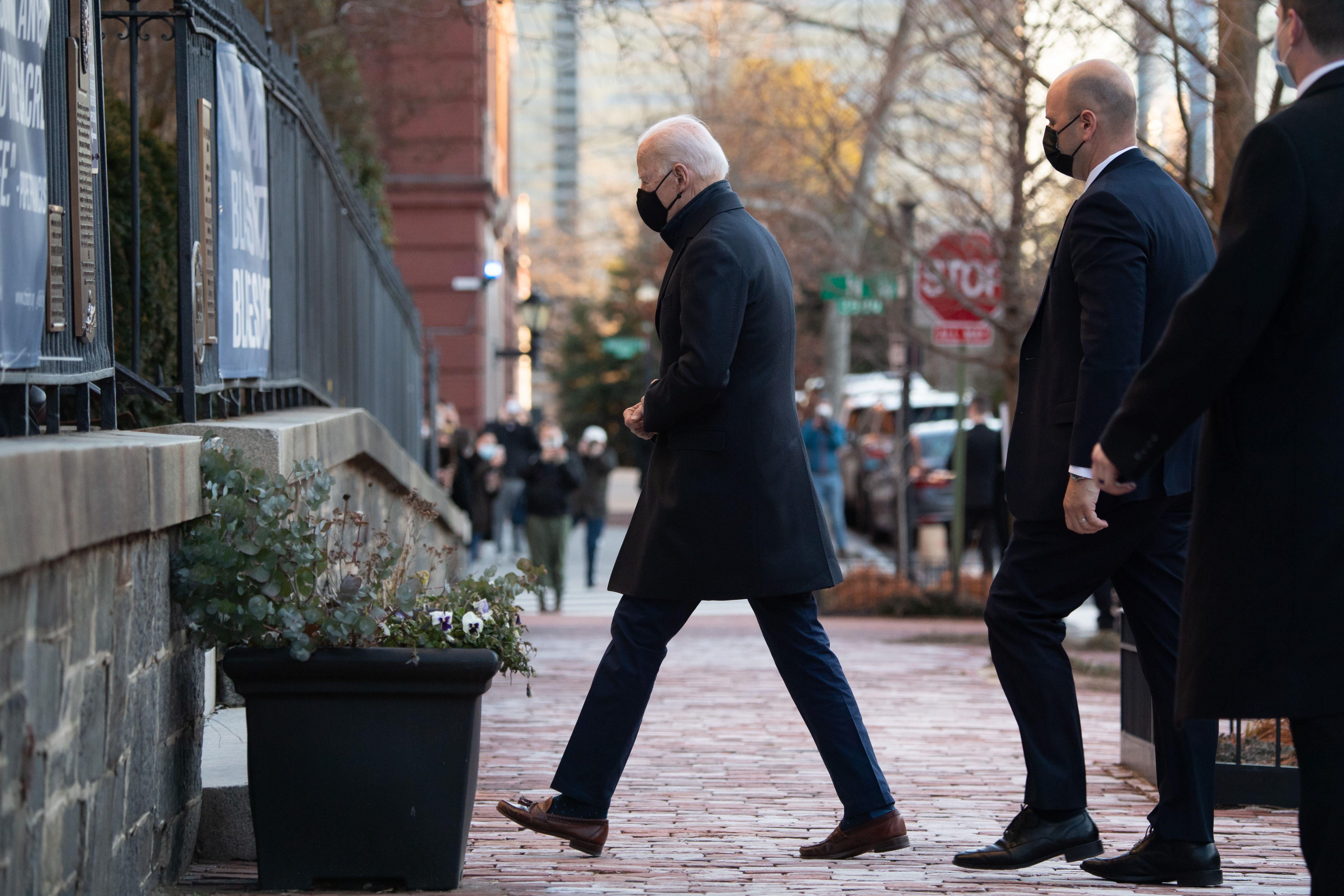 Biden walks across a sidewalk into Holy Trinity Catholic Church in Washington on March 6, with security following behind him