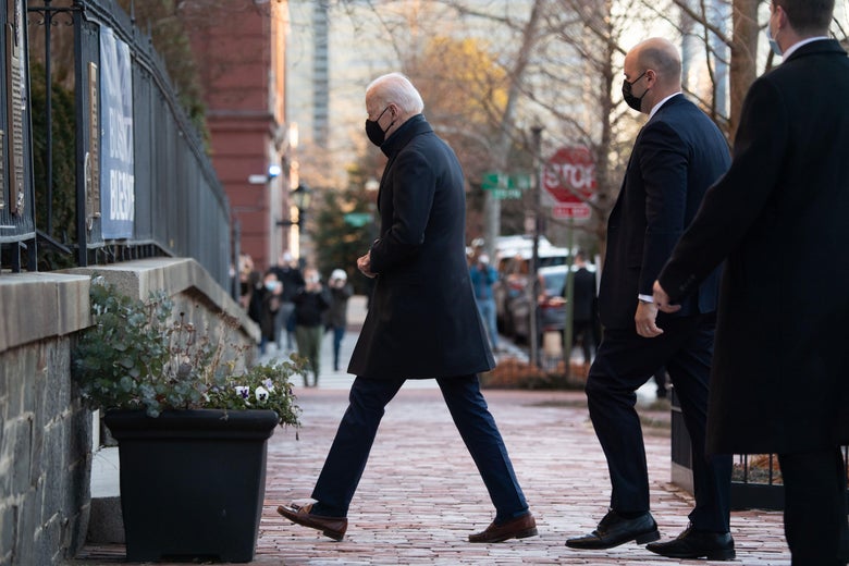 Biden walks across a sidewalk into Holy Trinity Catholic Church in Washington on March 6, with security following behind him