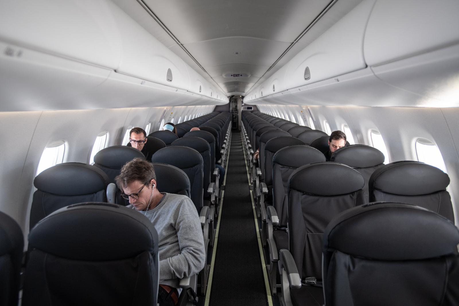 A handful of people seated in a nearly empty airplane cabin.