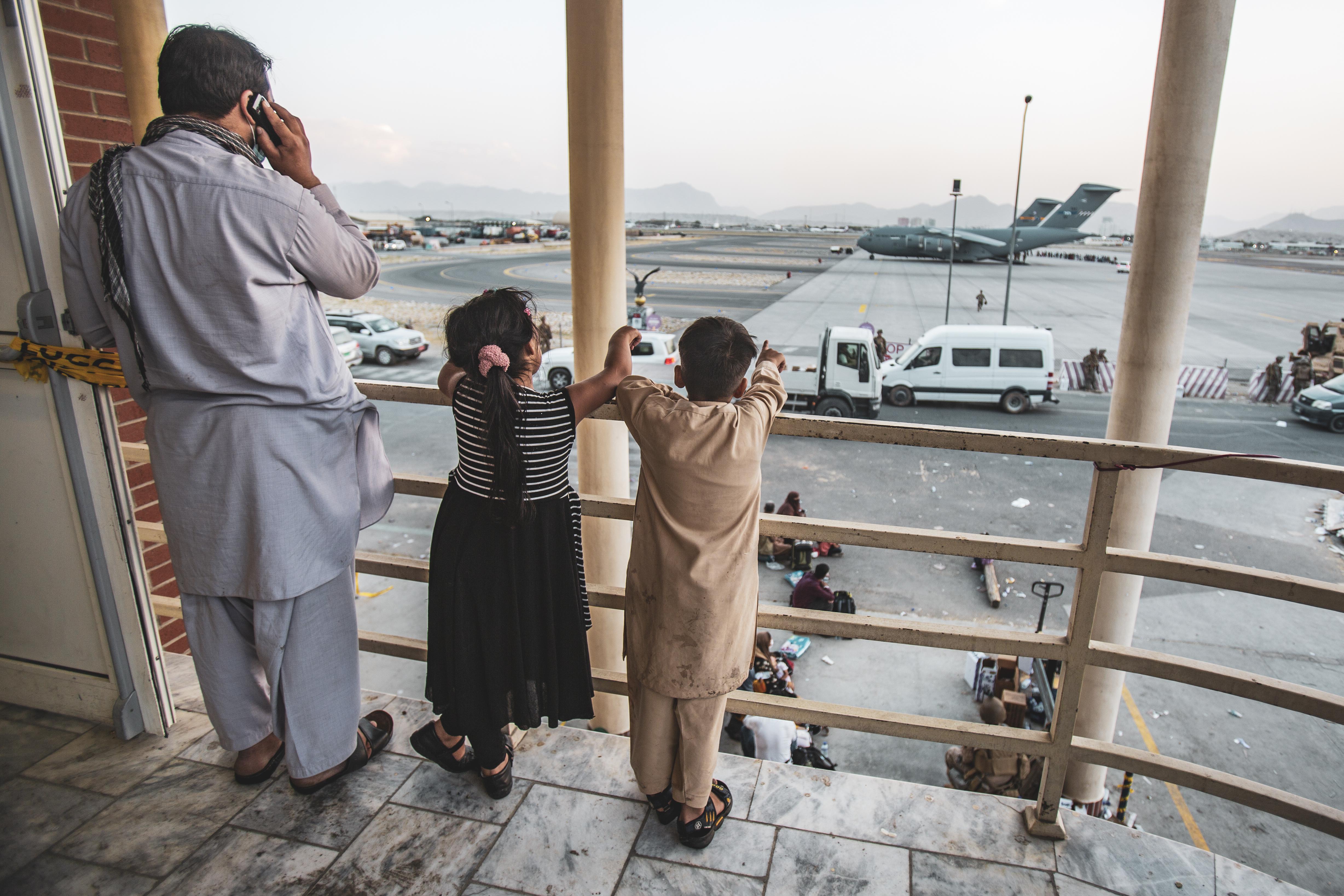 An Afghan family watches the evacuation underway at the Kabul airport.
