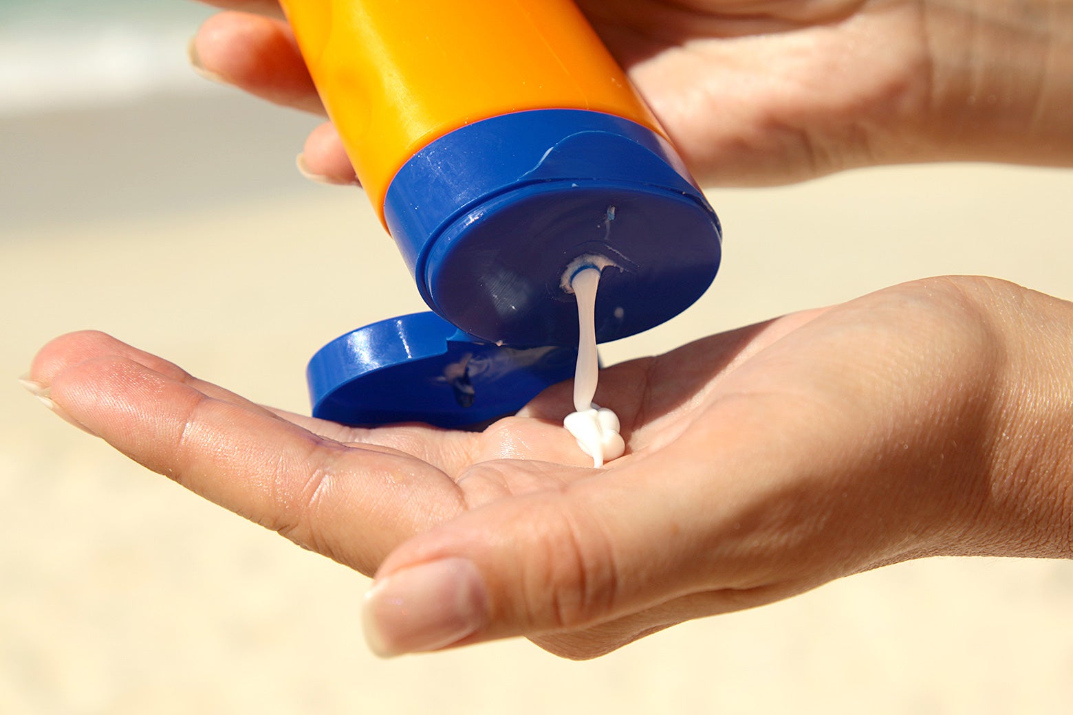 A woman squeezing sunscreen into her hand.