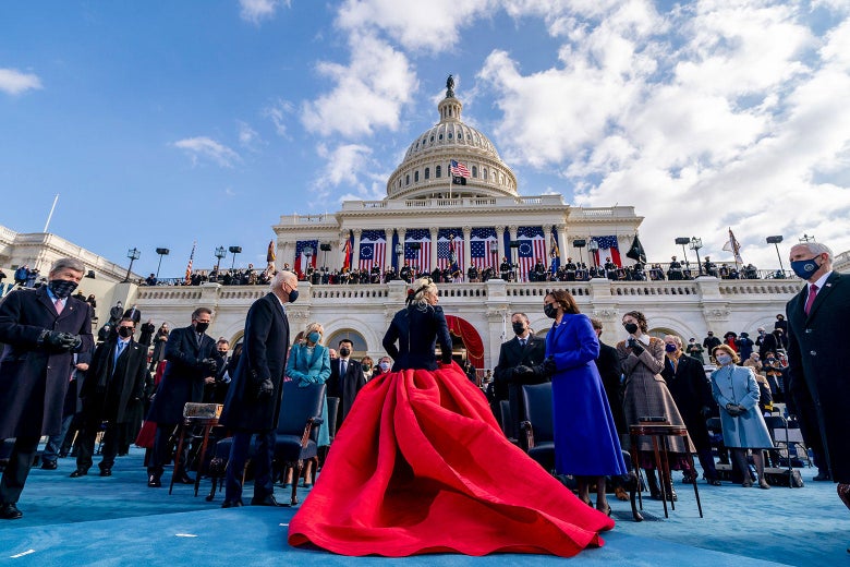 Lady Gaga in front of President Joe Biden and Vice President Kamala Harris. Gaga is wearing a voluminous red skirt with a black top.