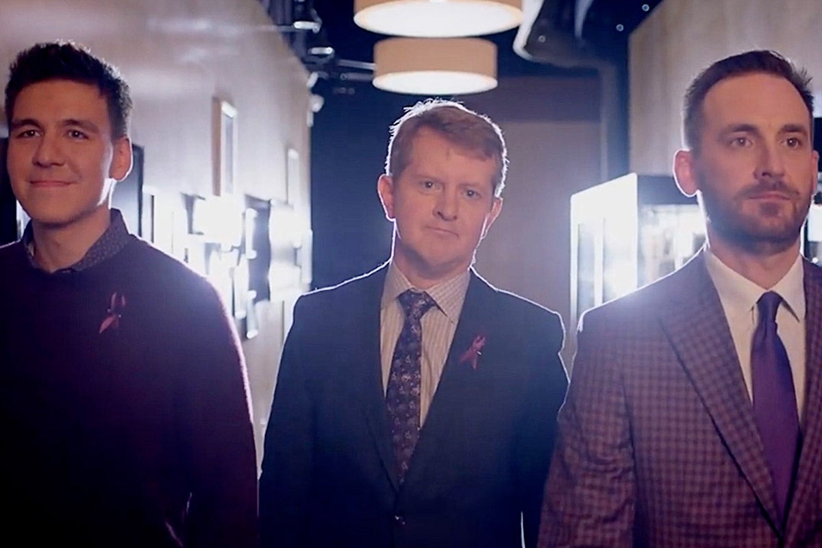 James Holzhauer, Ken Jennings, and Brad Rutter standing side by side in a hallway.