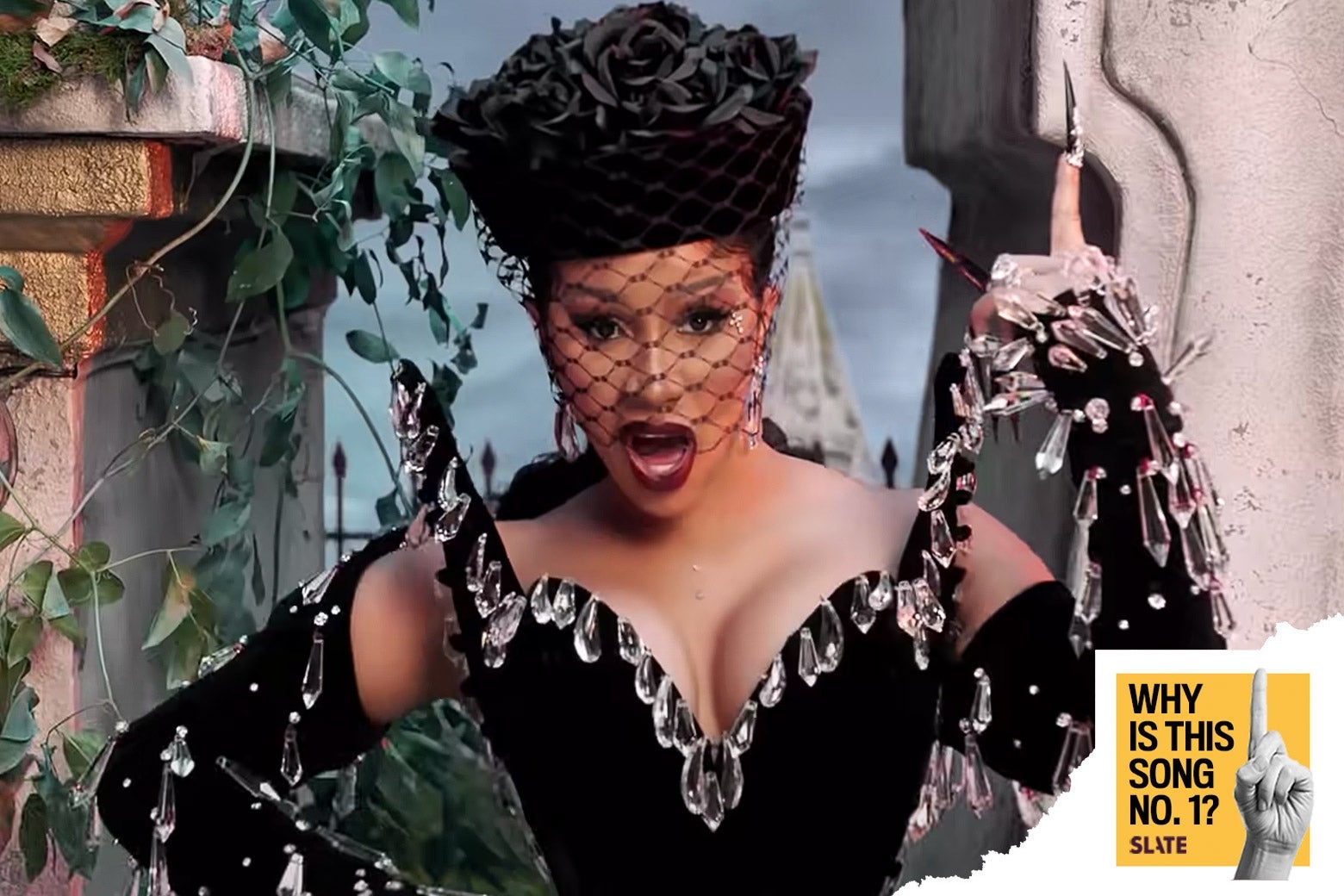 Cardi B in a black dress decorated with chandelier crystals.