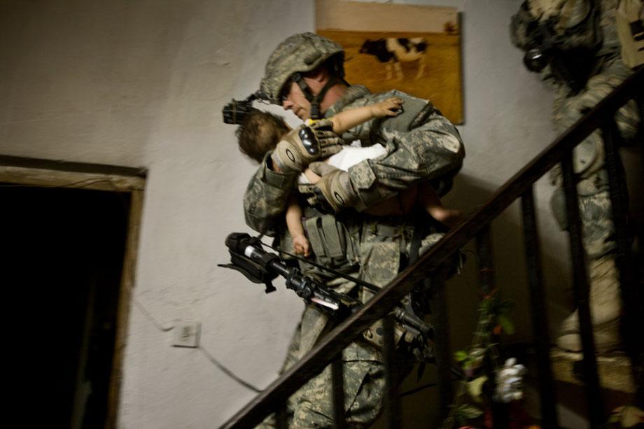 A soldier of Charlie Company, 1st Battalion, 21st Infantry Regiment “Gimlets,” 2nd Stryker Cavalry Regiment, attached to the 4th Infantry Division’s 3rd Brigade Combat Team, and Iraqi soliders of the 24th Brigade, 6th Iraqi Army Division, carries a child during a raid in Abu Ghraib, Anbar province, Iraq on April 6, 2008. The raid began before dawn this morning in which they sought out "high-value" al Qaeda targets involved in kidnapping and murder. They searched several houses but did not find the suspects they were looking for.
