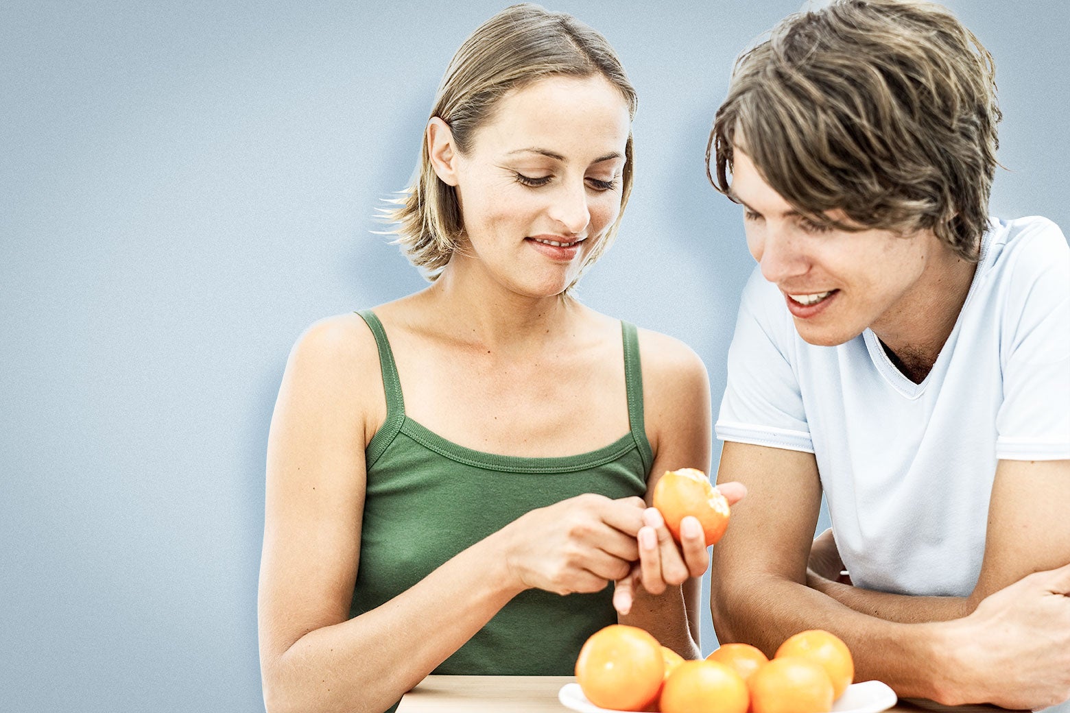 A heterosexual white man-woman couple peel an orange together to test the orange-peel theory. 
