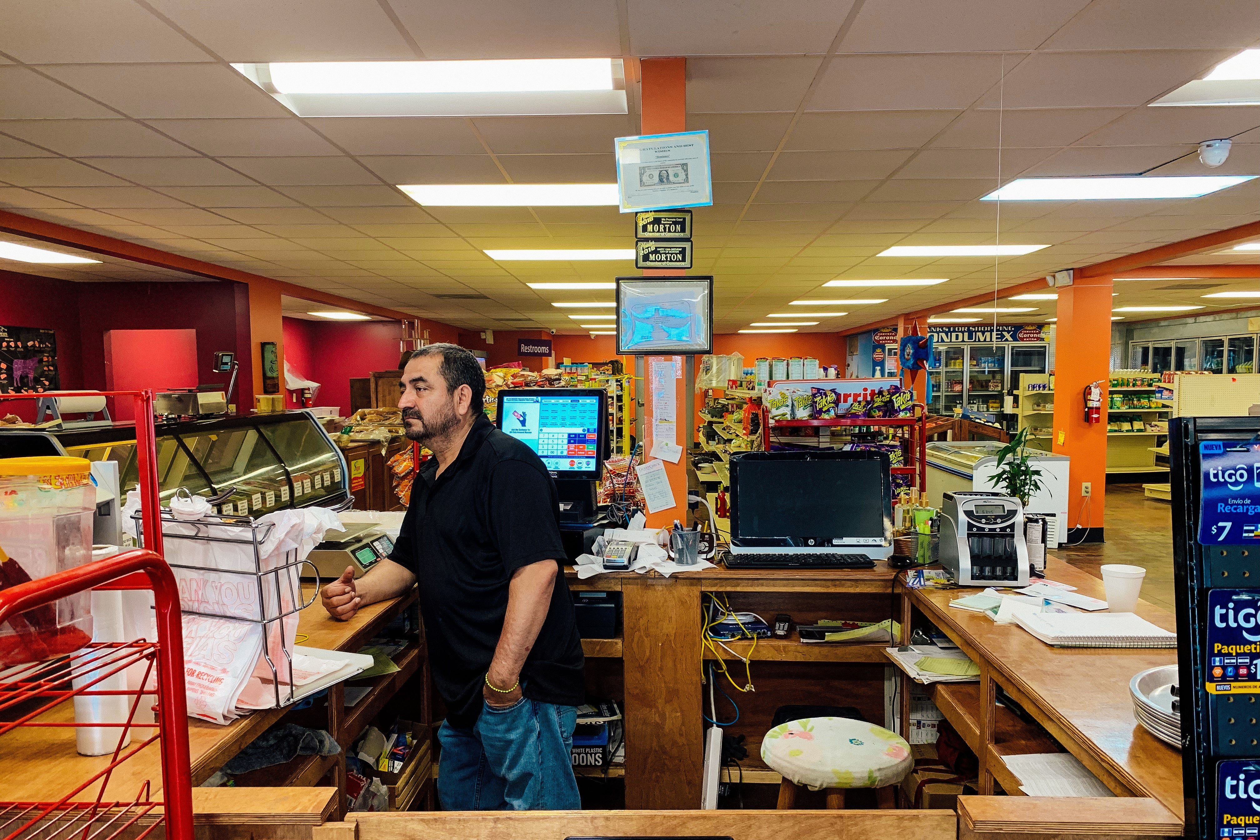 Juan Garcia stands at the register of his deserted grocery store.